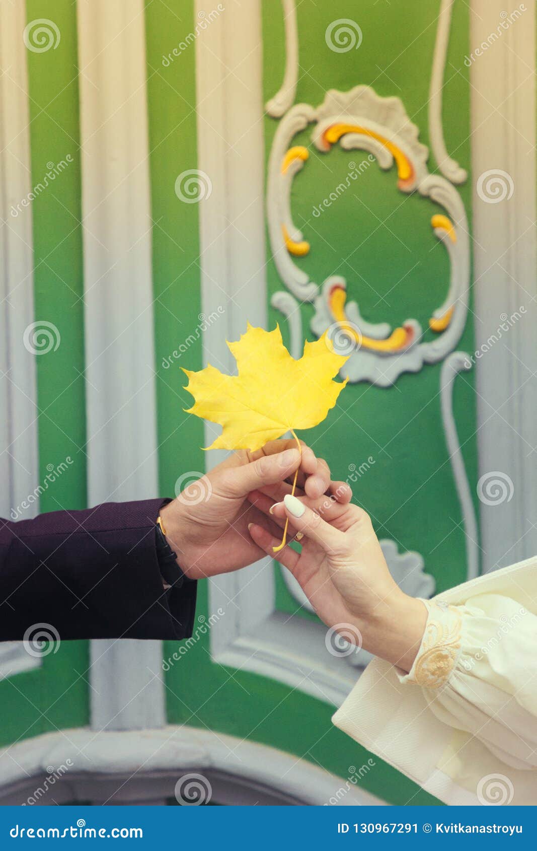 Male And Female Hands Holding Amaple Leaf On The Green Door