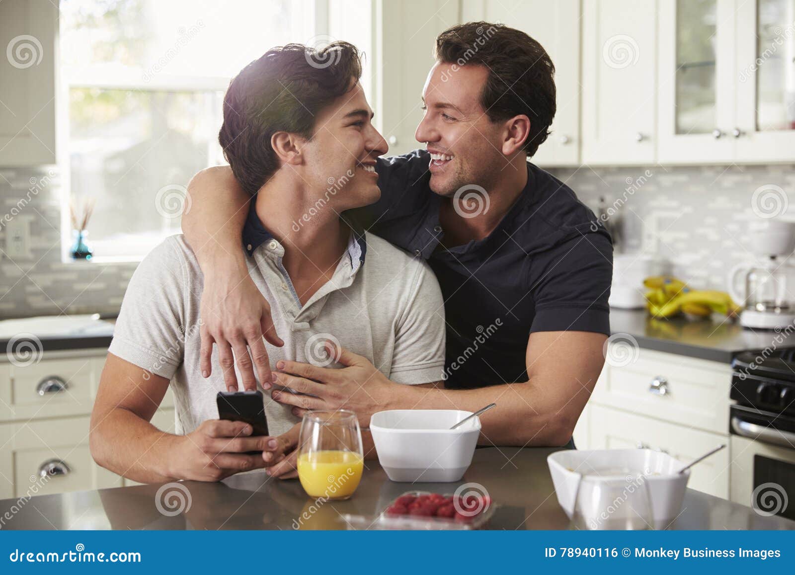 male gay couple in their 20s embracing in their kitchen