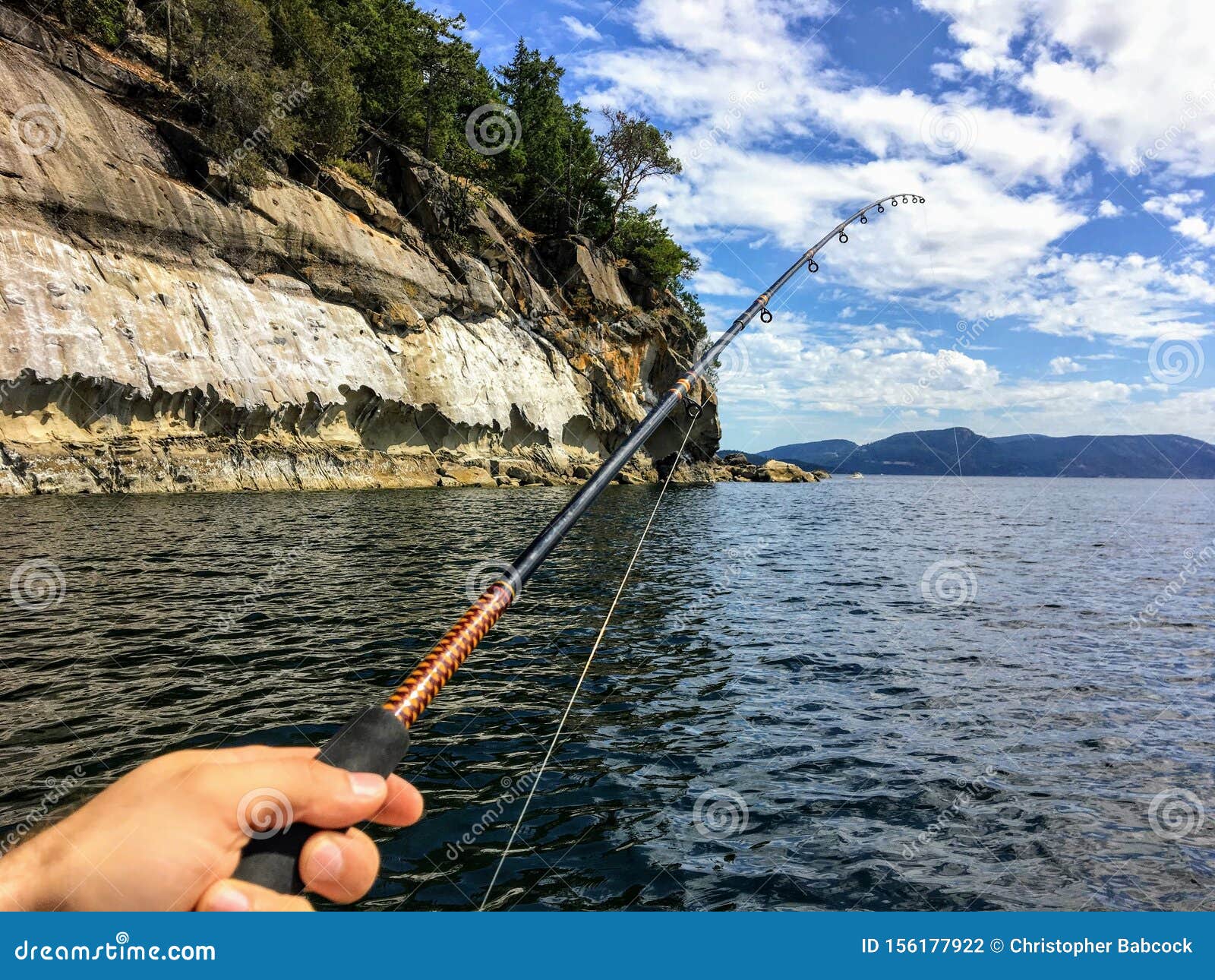 A Male Hand Holding a Fishing Rod Jigging for Fish with the