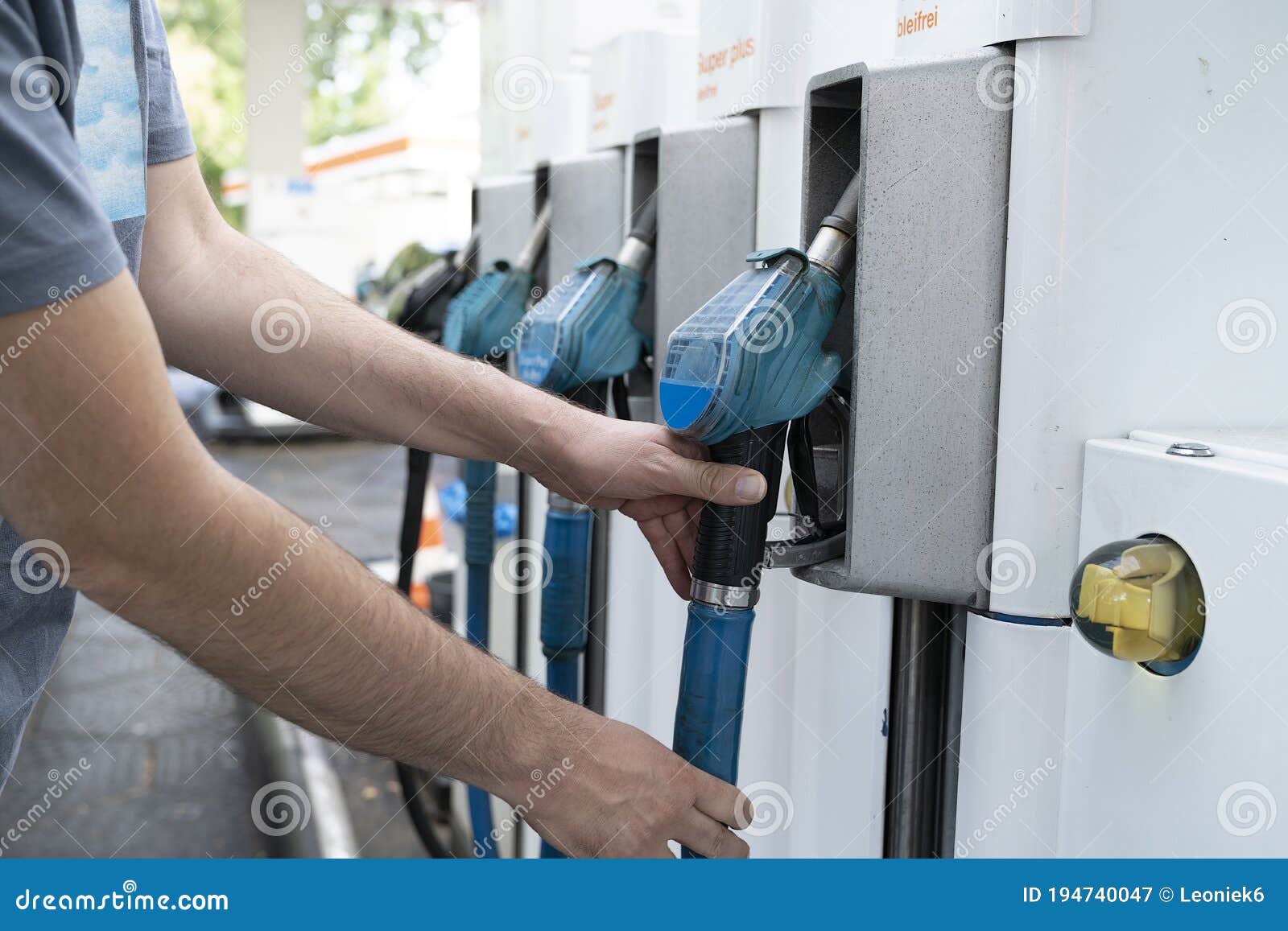 male hand places gaspump nozzle back in the pump at the gasstation