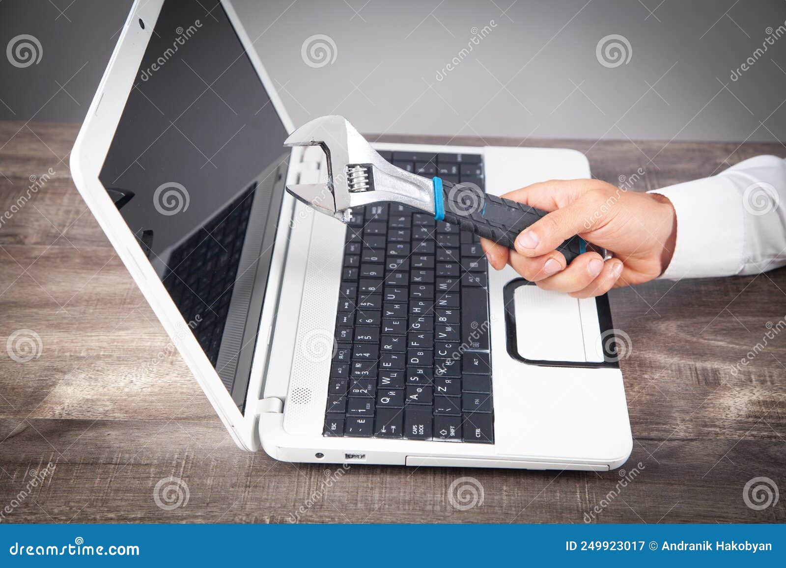 Male Hand Showing Adjustable Wrench Over Computer Keyboard. it Service