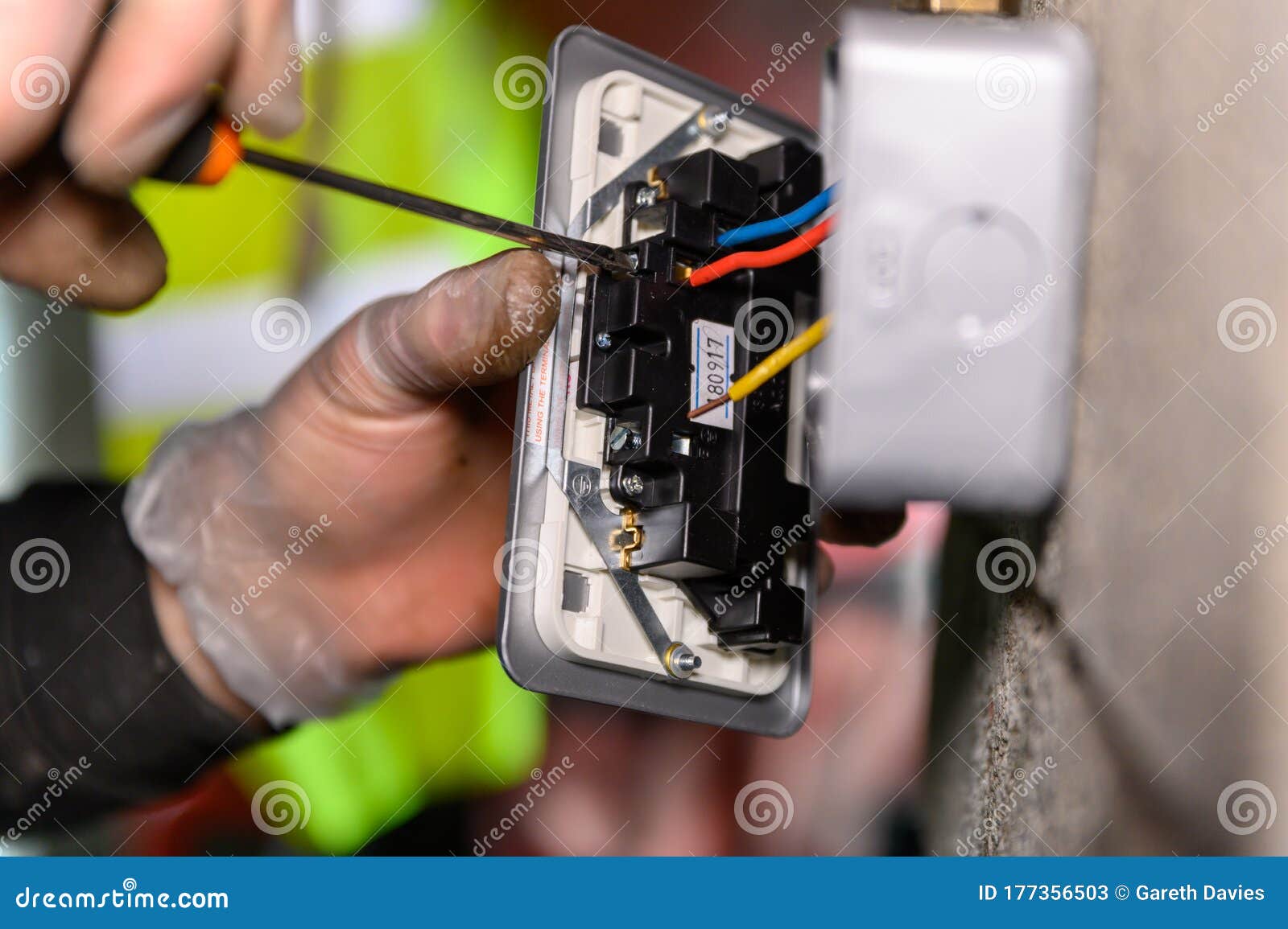 male hands wiring a uk socket plug on garage wall with screw driver