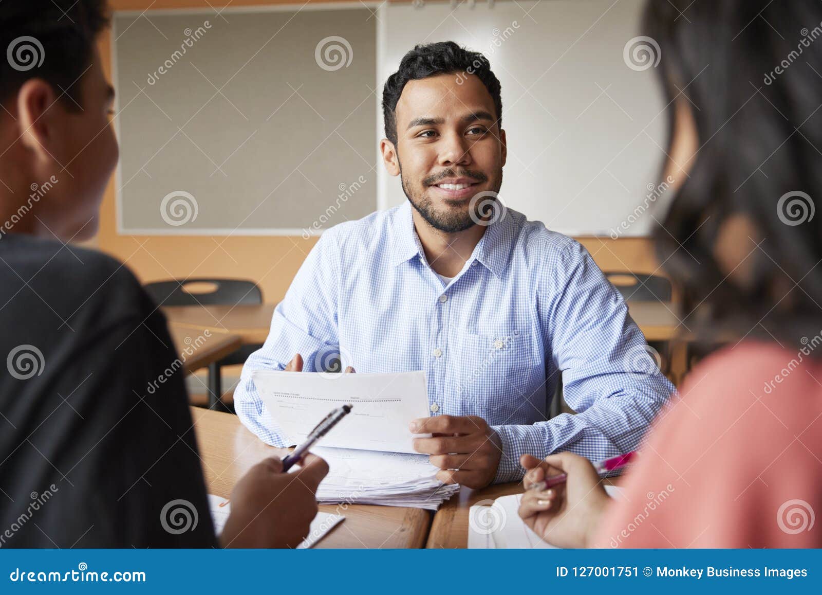 male high school tutor with two students at desk in seminar