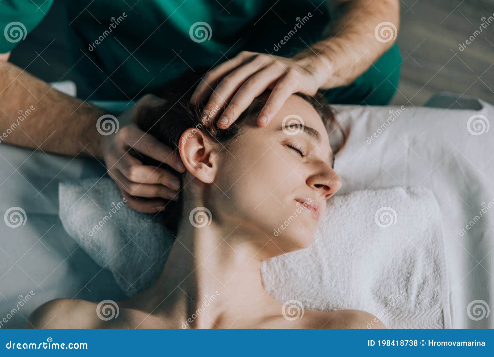 Male Massage Therapist Makes Face Massage To A Young Beautiful Woman Head Turned To The Side