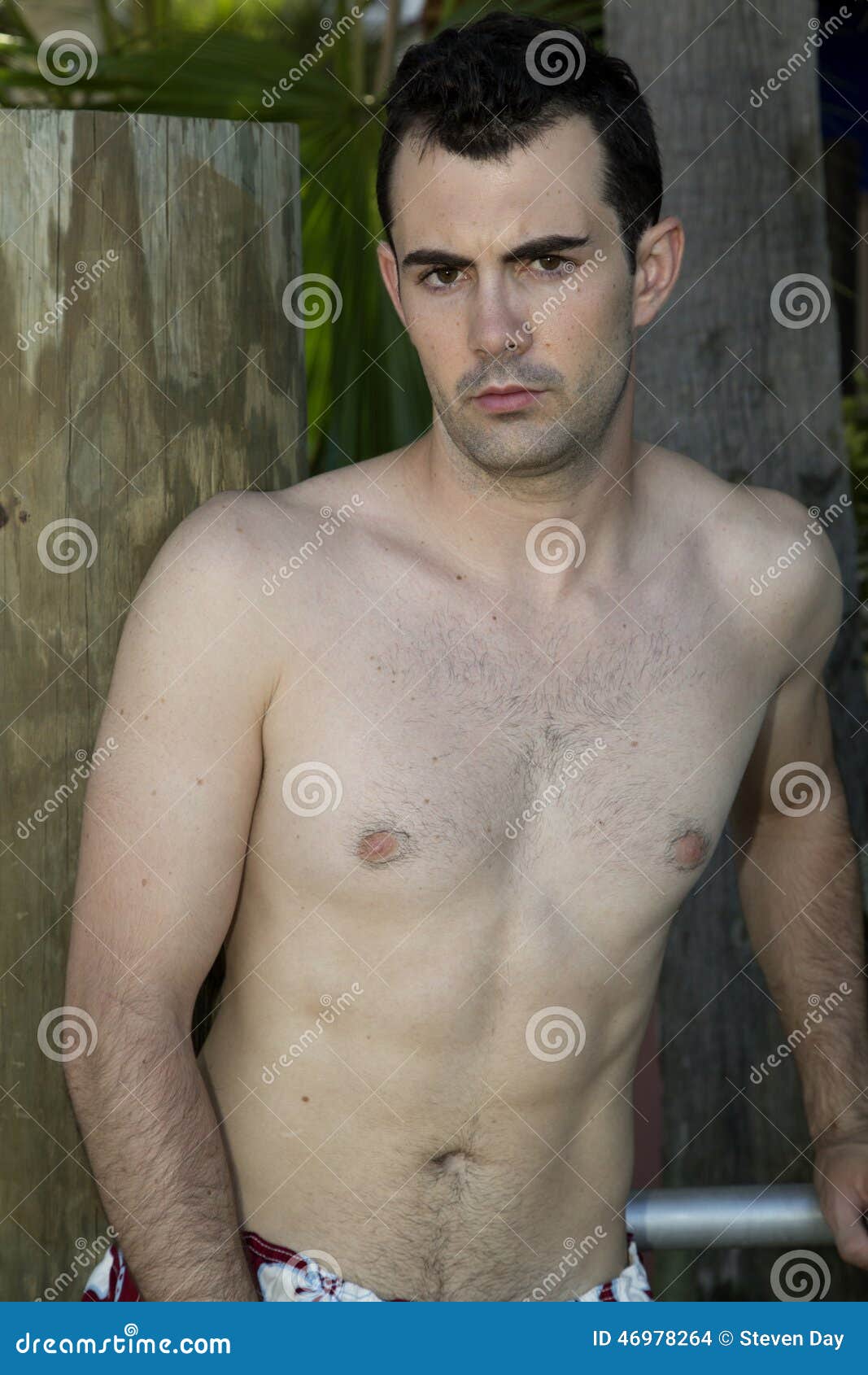 male model glaring at camera with no shirt wearing swimsui