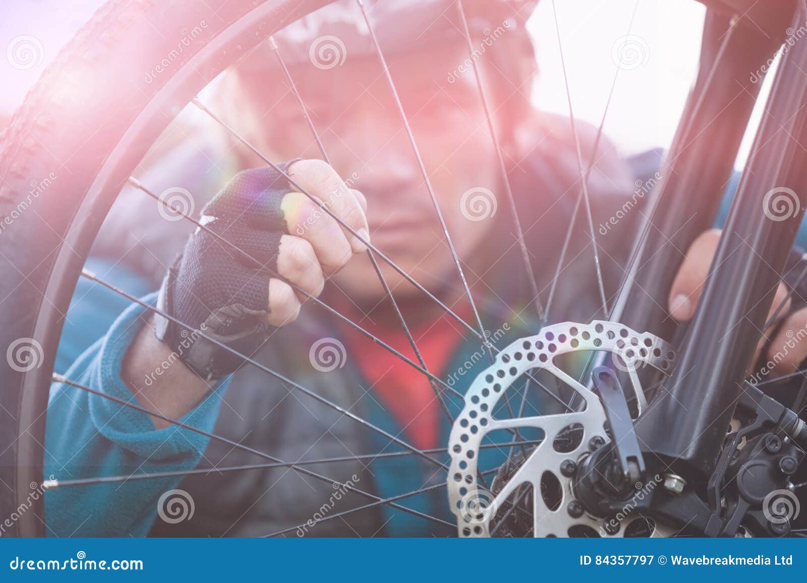 Male Mountain Biker Examining Front Wheel of His Bicycle Stock Image