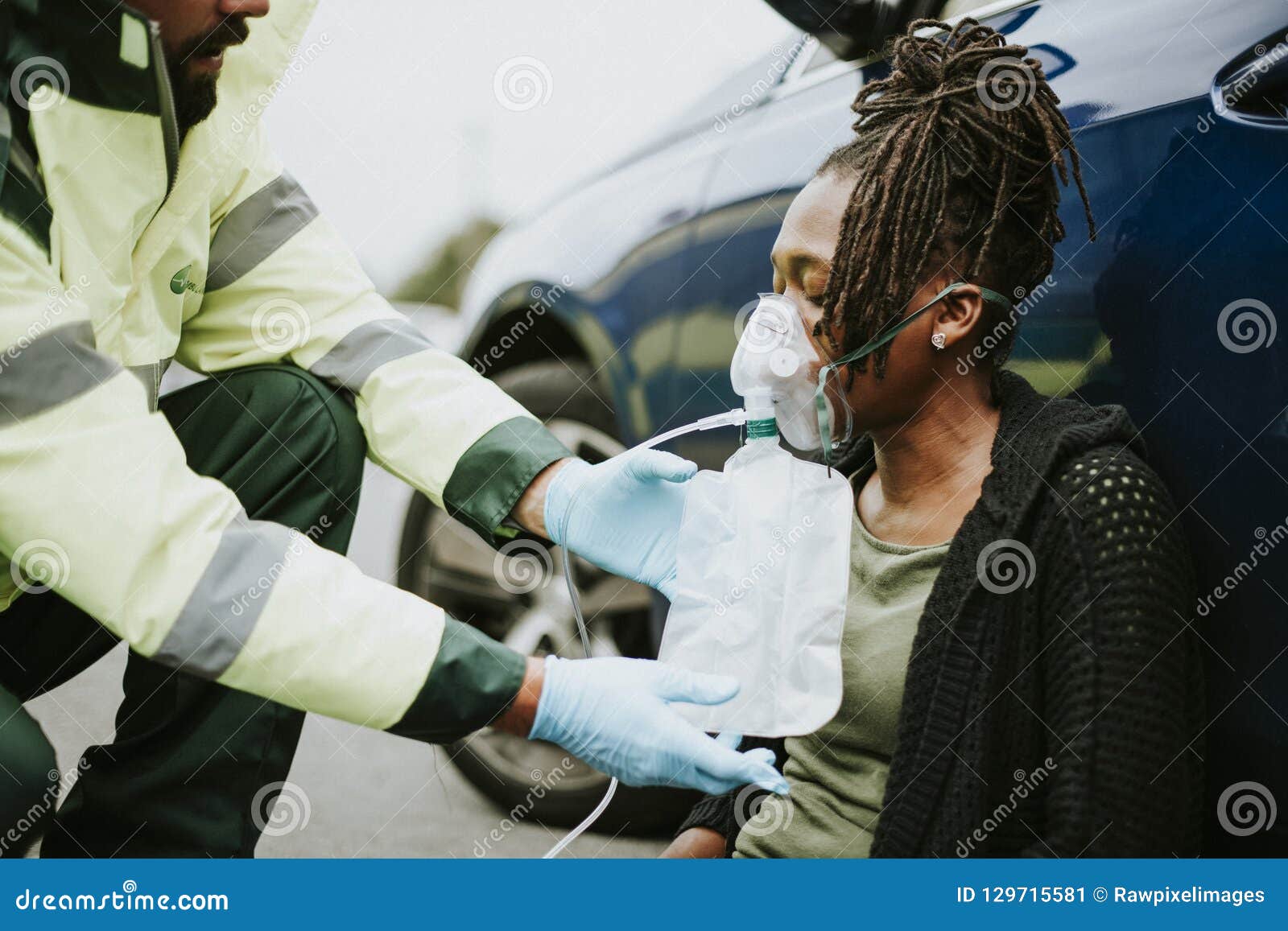 male paramedic putting on an oxygen mask to an injured woman on a road