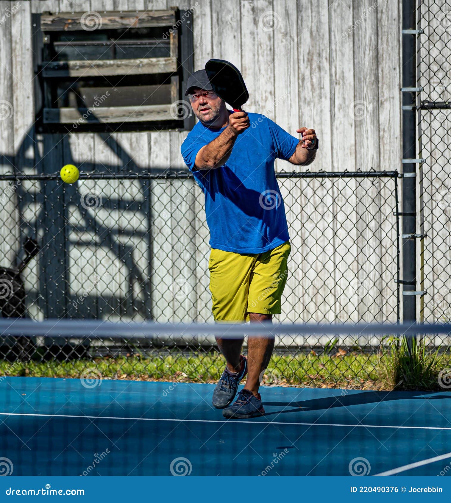 Male Pickleball Player Hits the Ball from the Baseline Stock Photo