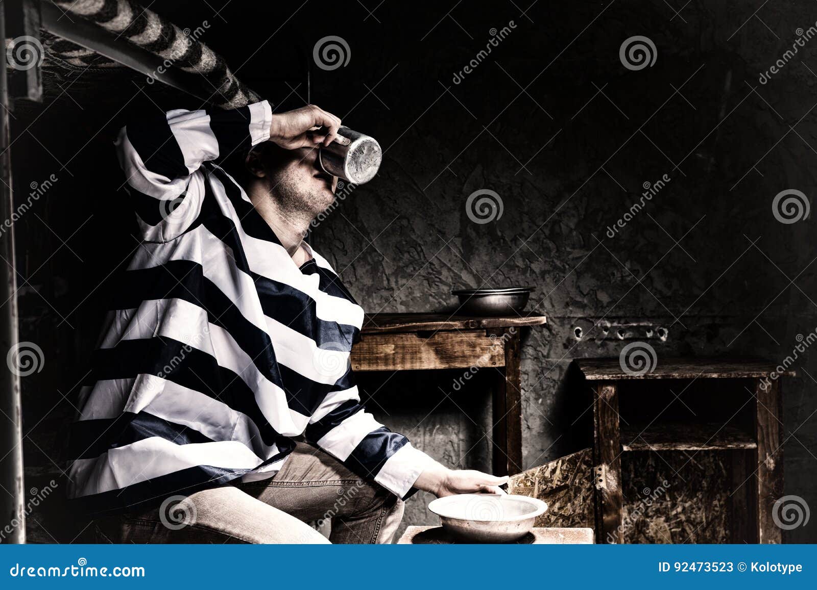 Male Prisoner Drinking from an Aluminum Cup in a Prison Cell Stock