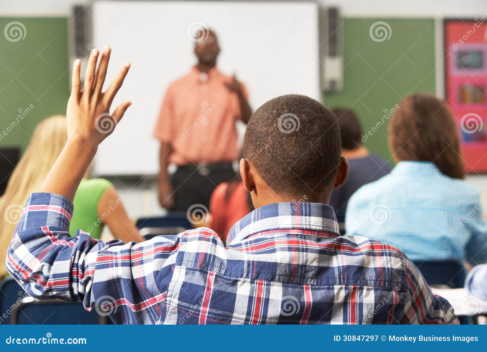 male pupil raising hand in class