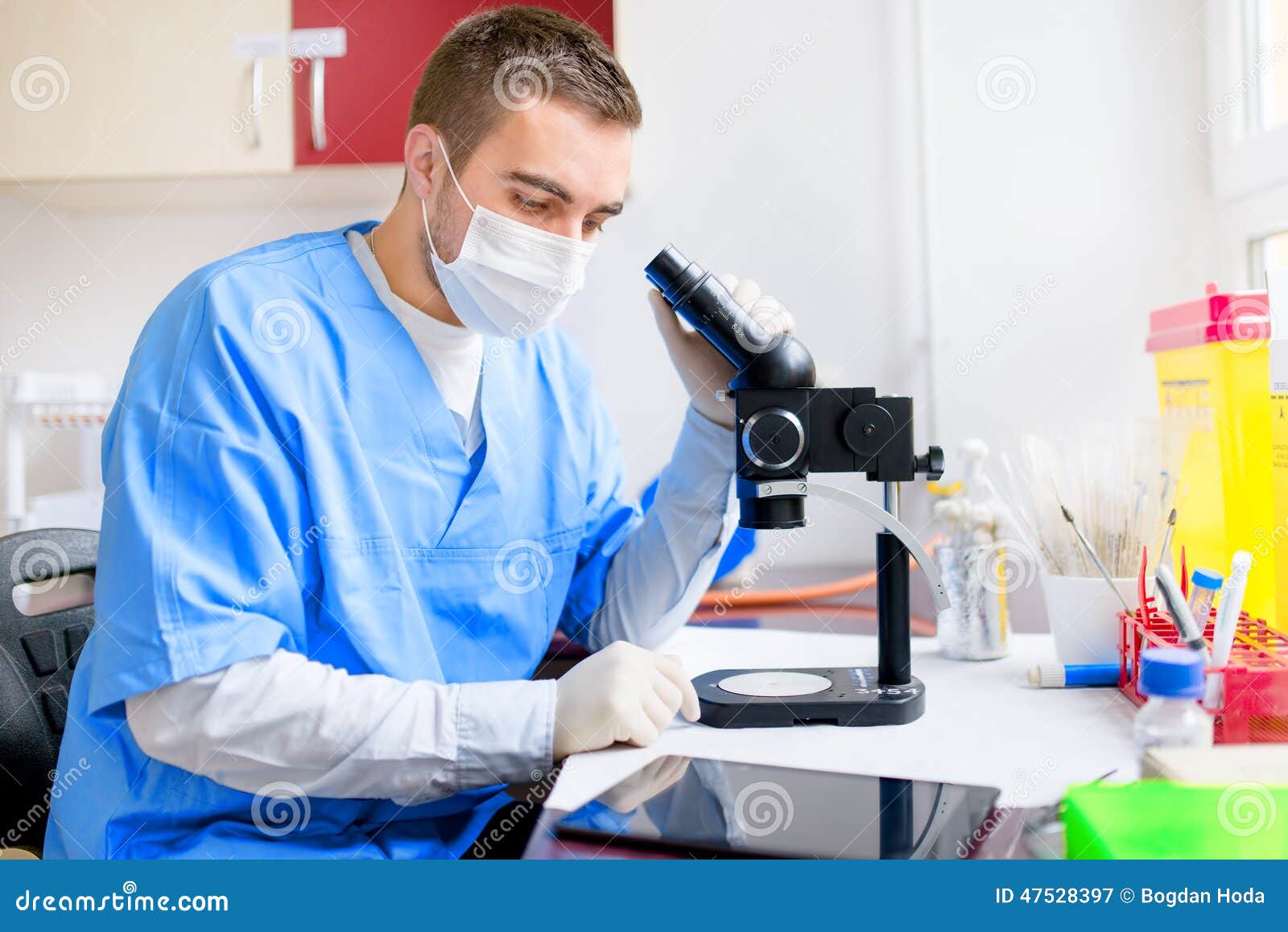 Male researcher carrying out scientific research in a laboratory using tablet and microscope