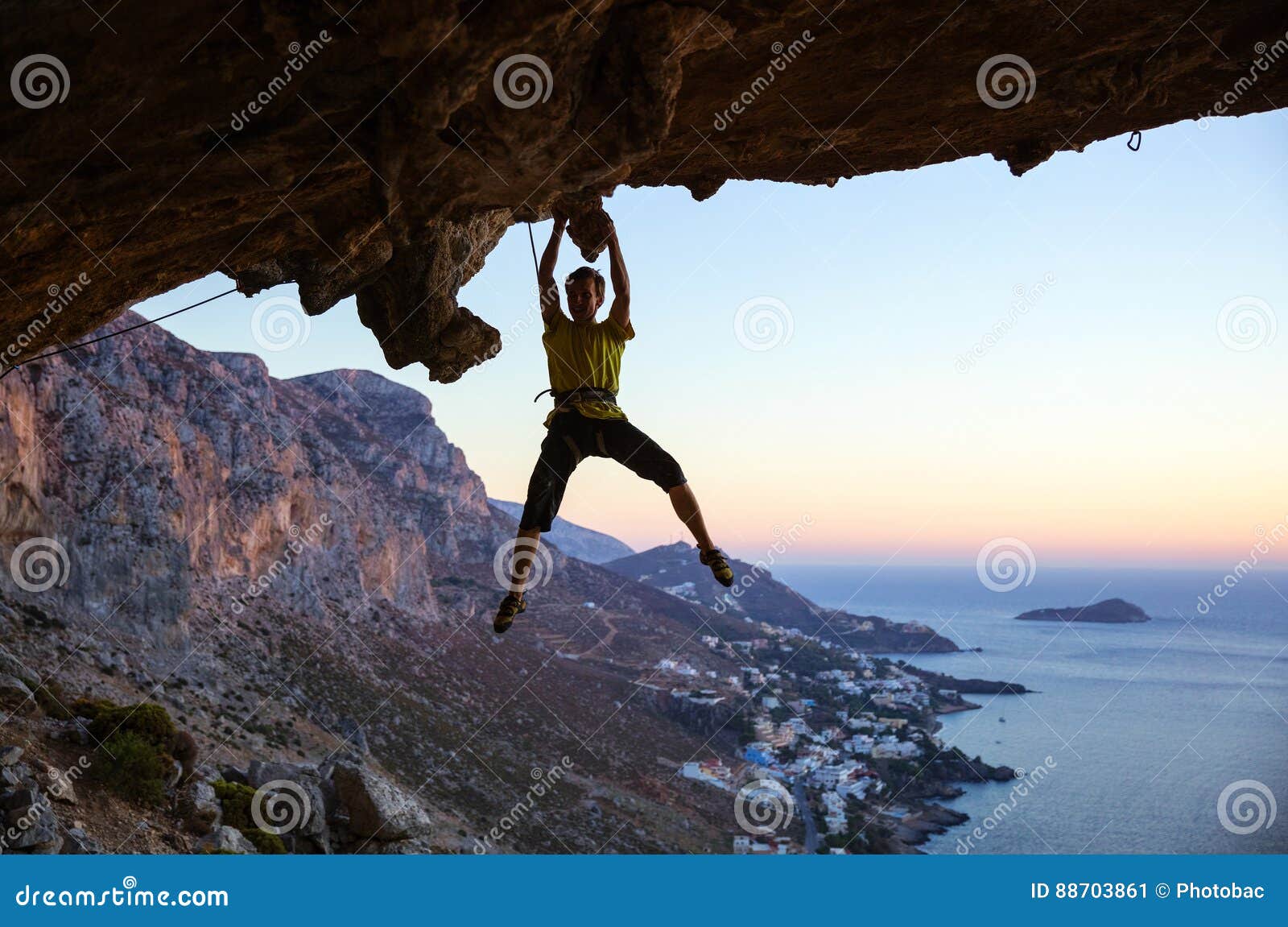 male rock climber gripping handhold on ceiling in cave