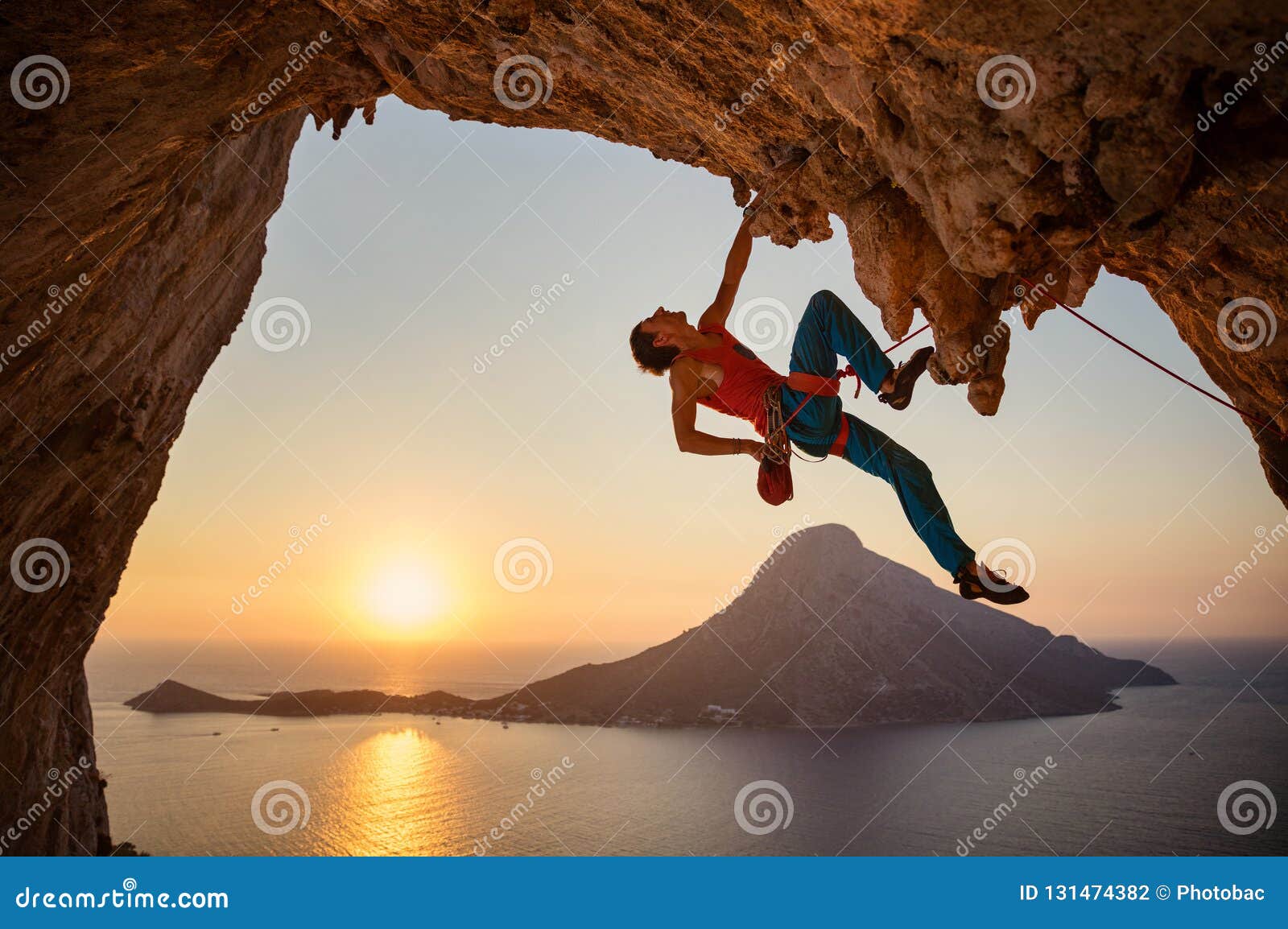 male rock climber hanging with one hand on challenging route on cliff