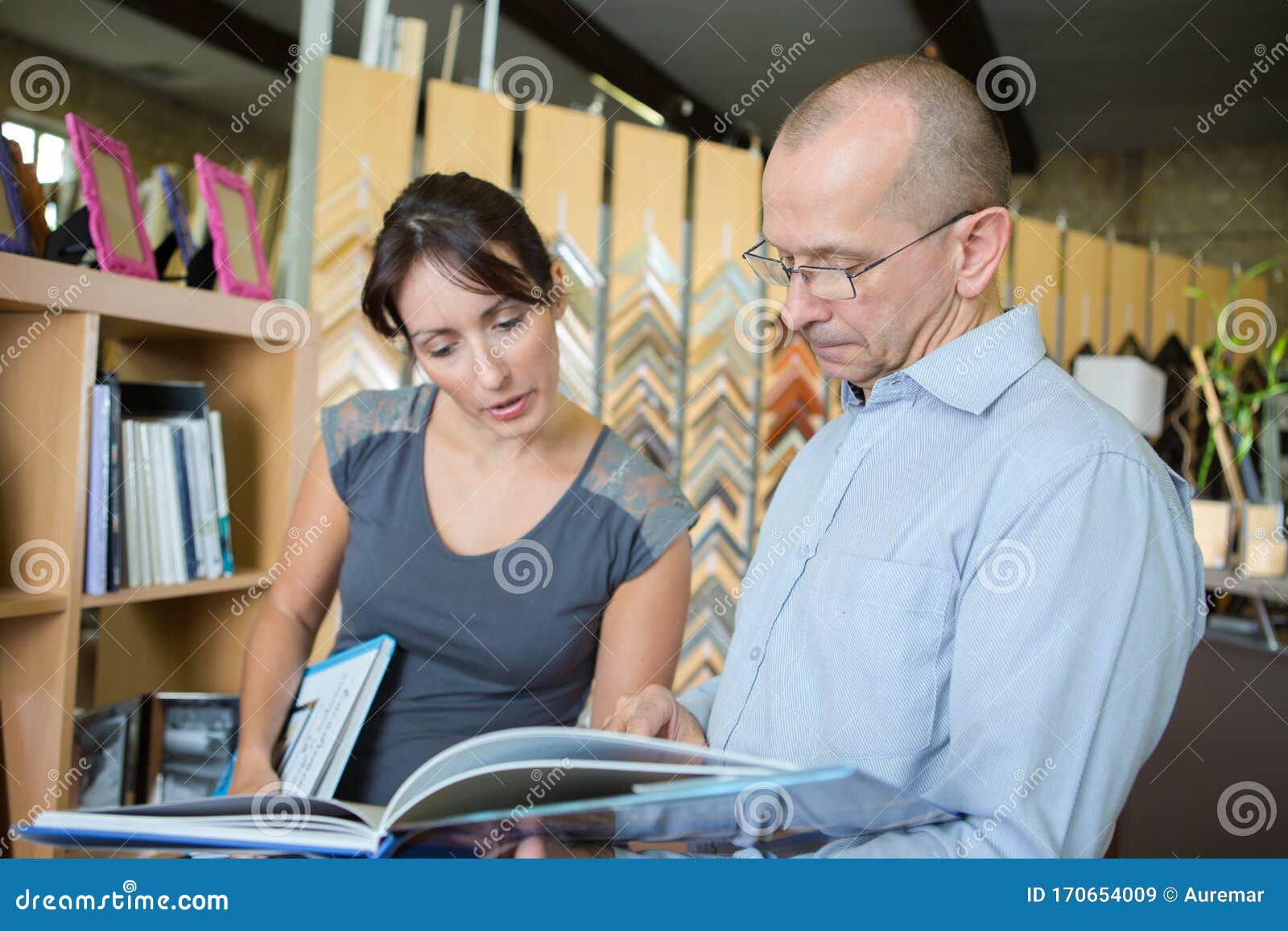 Male Seller Standing in Picture Framing Studio with Customer Stock