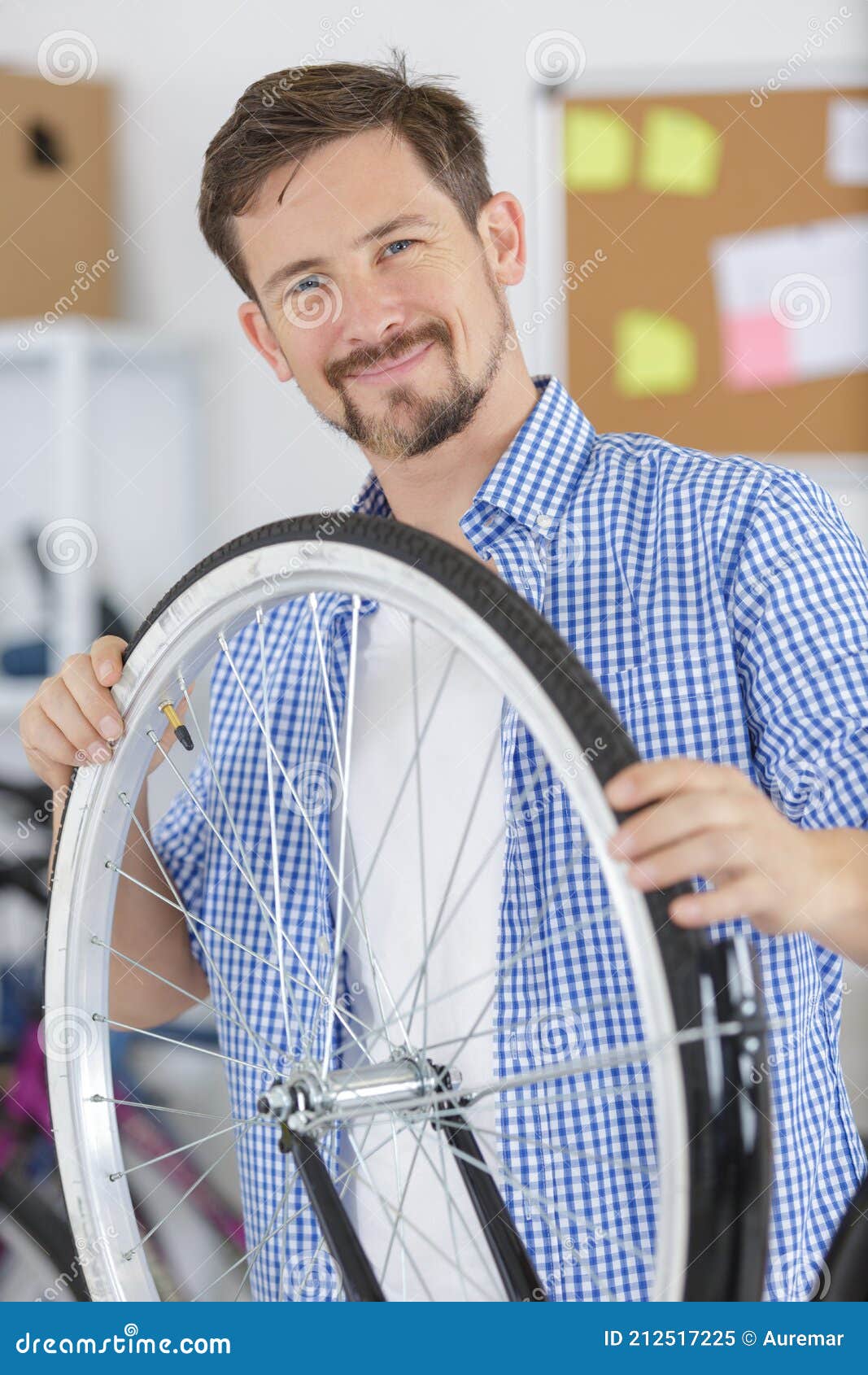 male smiling master holding bike wheel