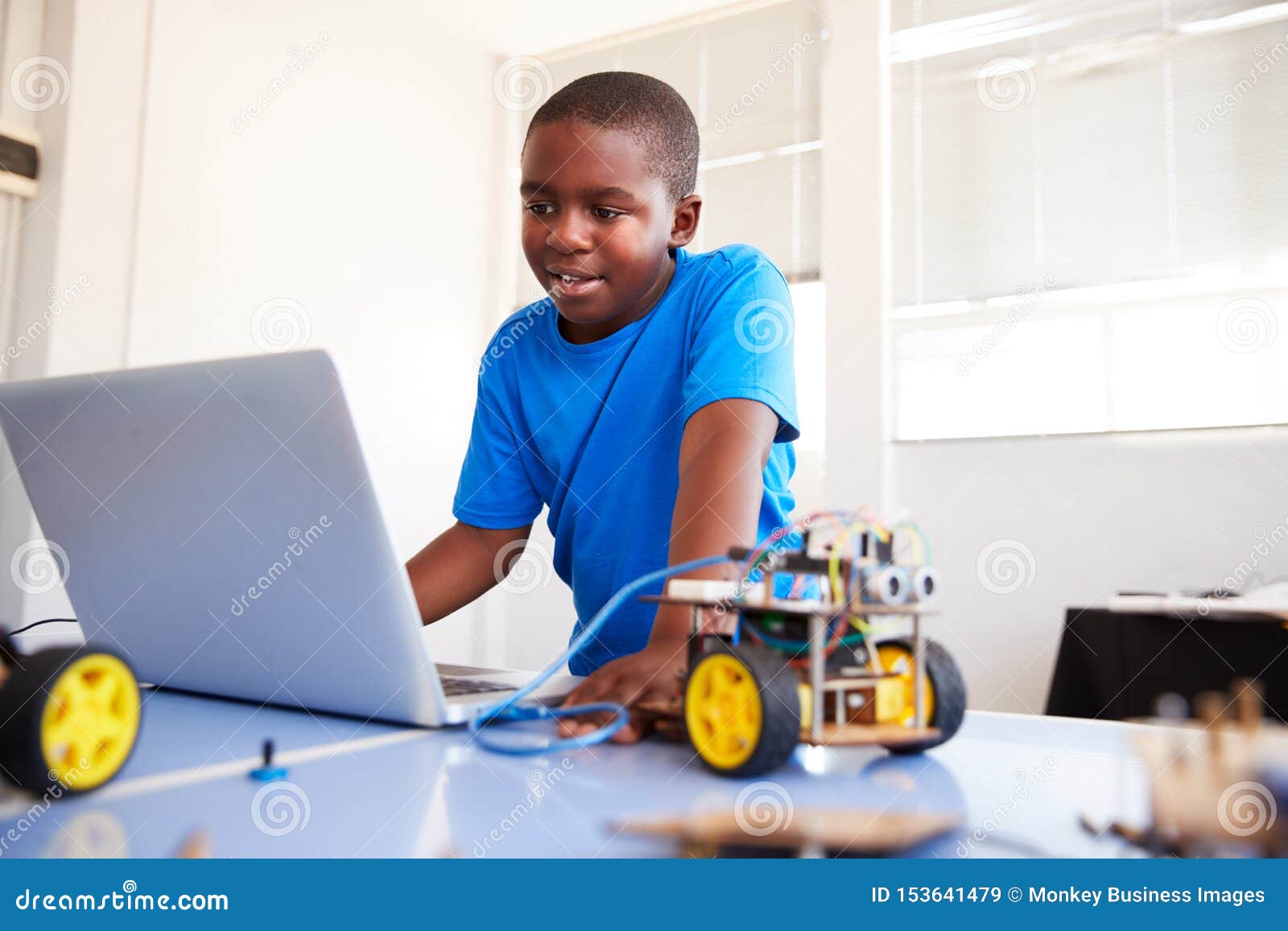male student building and programing robot vehicle in after school computer coding class