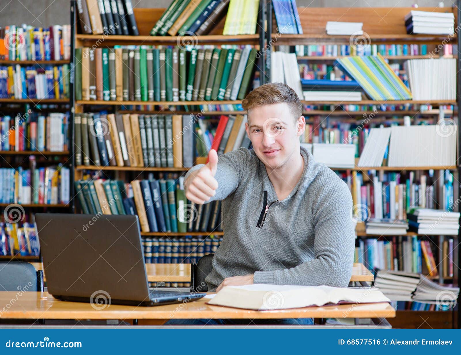Male Student with Laptop Showing Thumbs Up in the University Library ... pic