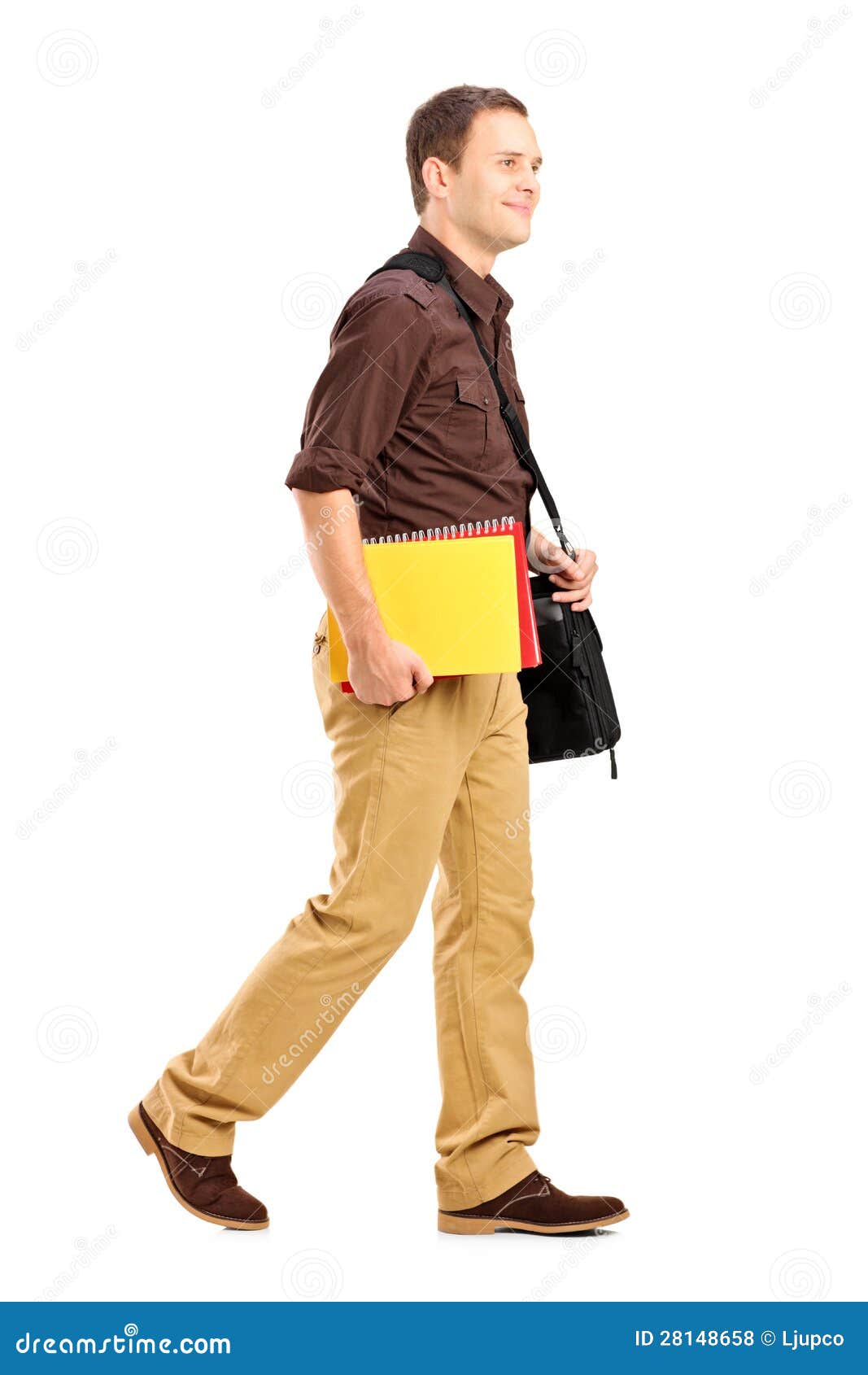 Male Student With Shoulder Bag Holding Books And Walking Stock Photo