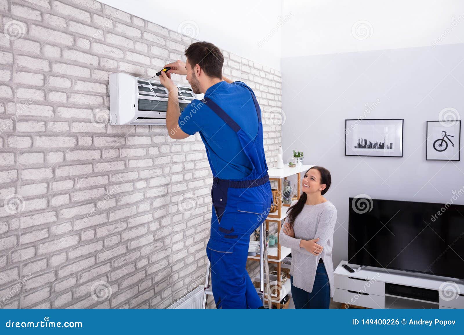 male technician repairing air conditioner with screwdriver