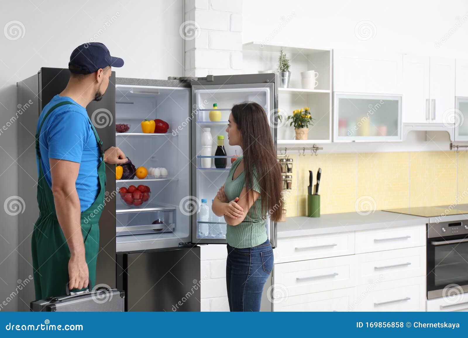 Male Technician Talking with Client Near Refrigerator Stock Photo