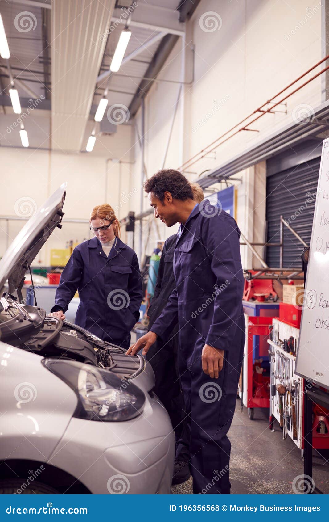 Male Tutor with Students Looking at Car Engine on Auto Mechanic