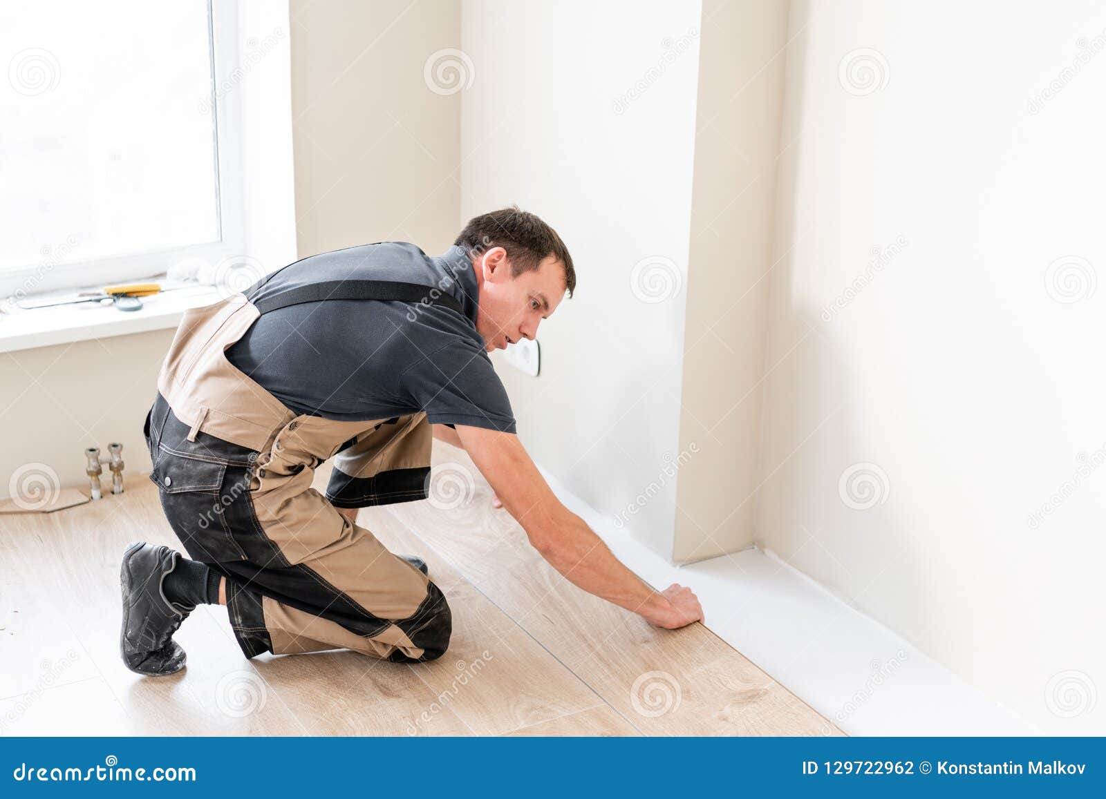 Male Worker Installing New Wooden Laminate Flooring On A Warm Film