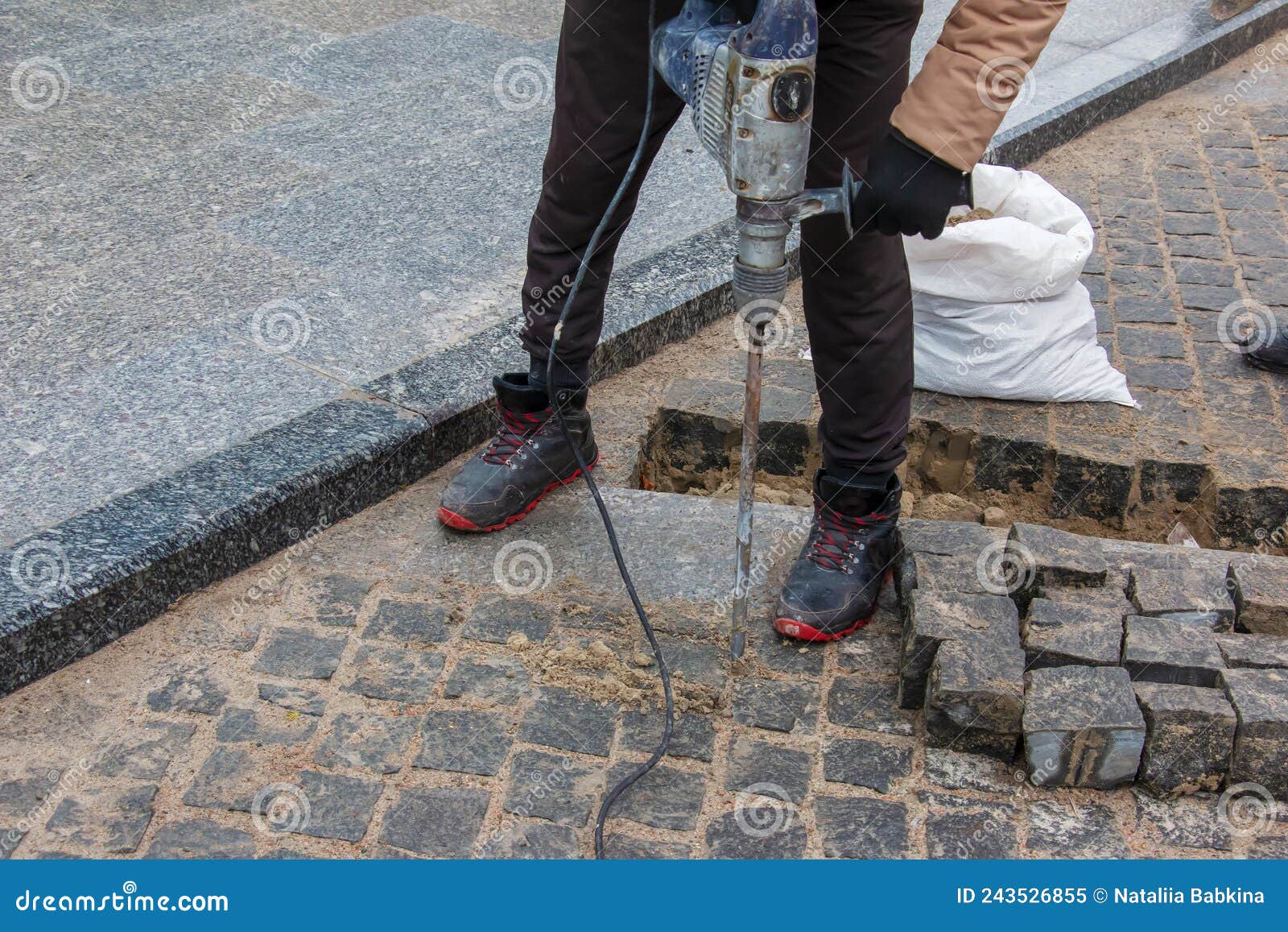 A Male Worker Repairs the Pavement with a Jackhammer. the Work of the