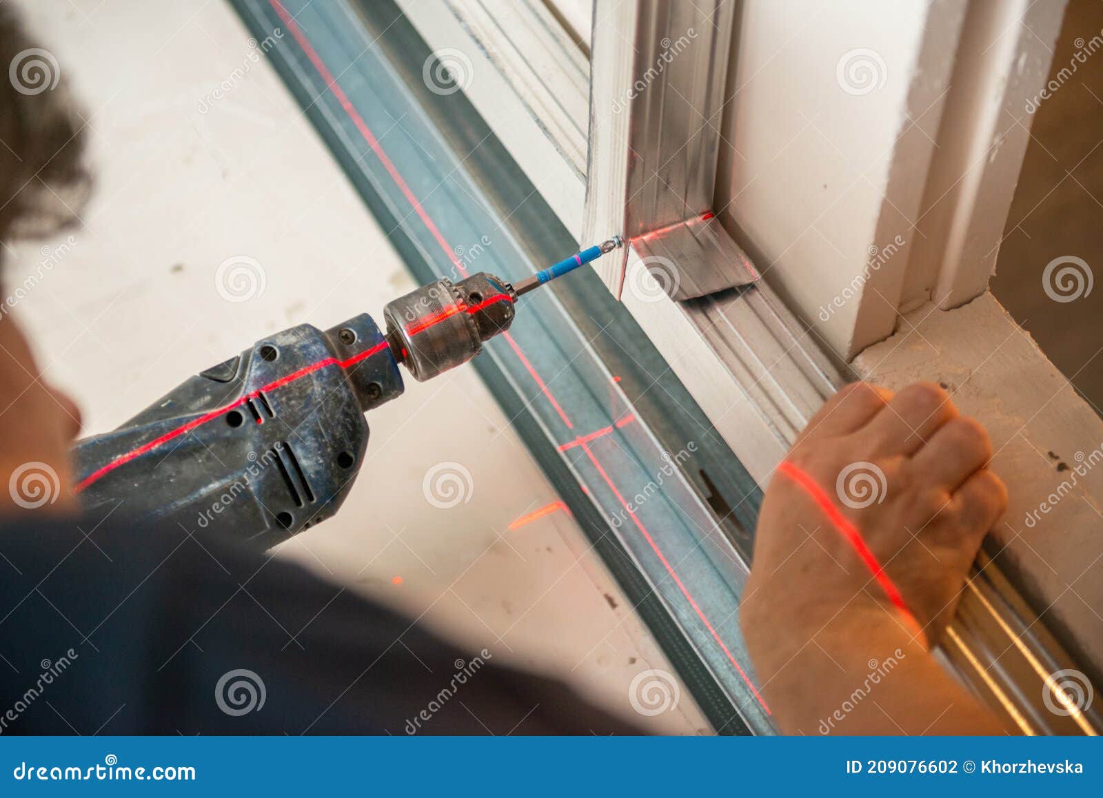 male worker works with profile for drywall, setting, assembling with drill. construction work, repair