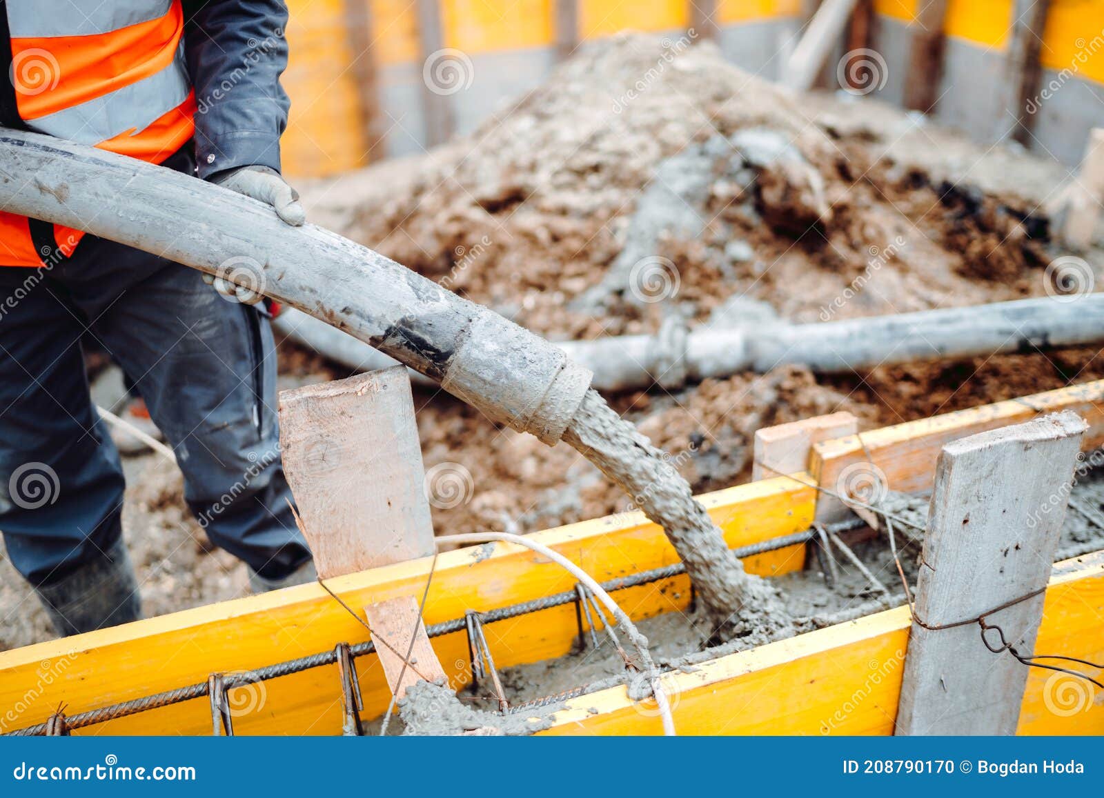 male workers pouring concrete with concrete hose. details of construction site and close up details of worker workwear