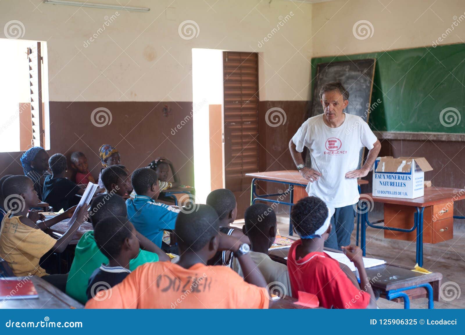 White Senior Man Teaching Black Children In Africa