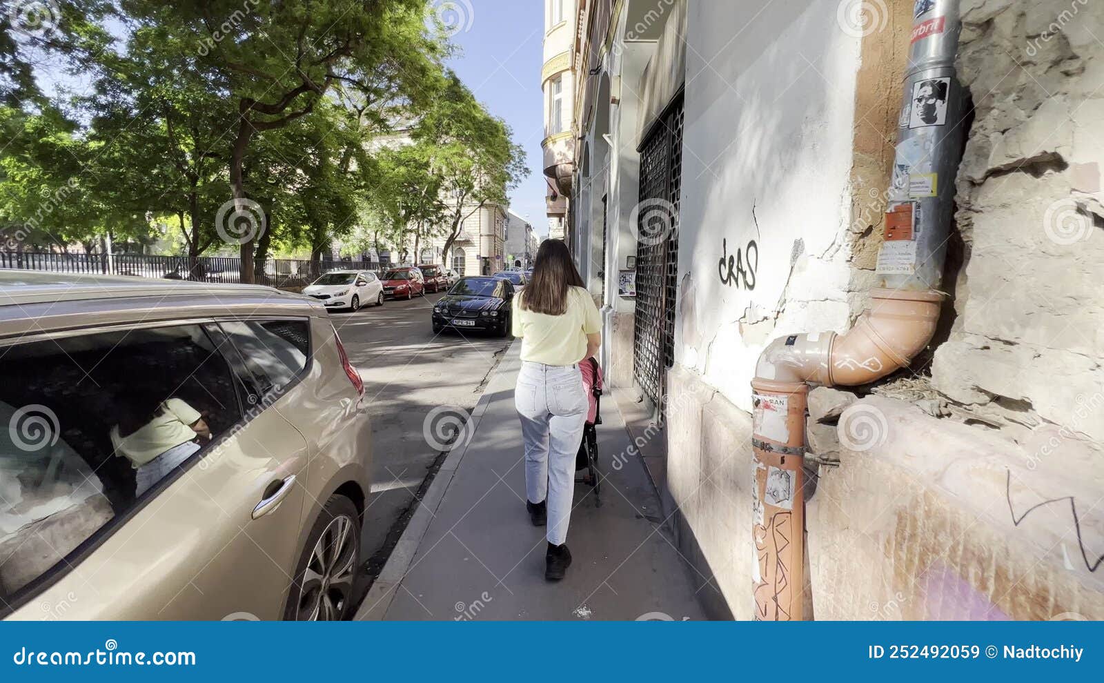 Jeune Femme Qui Pousse Son Bébé Dans La Poussette Sur Le Trottoir