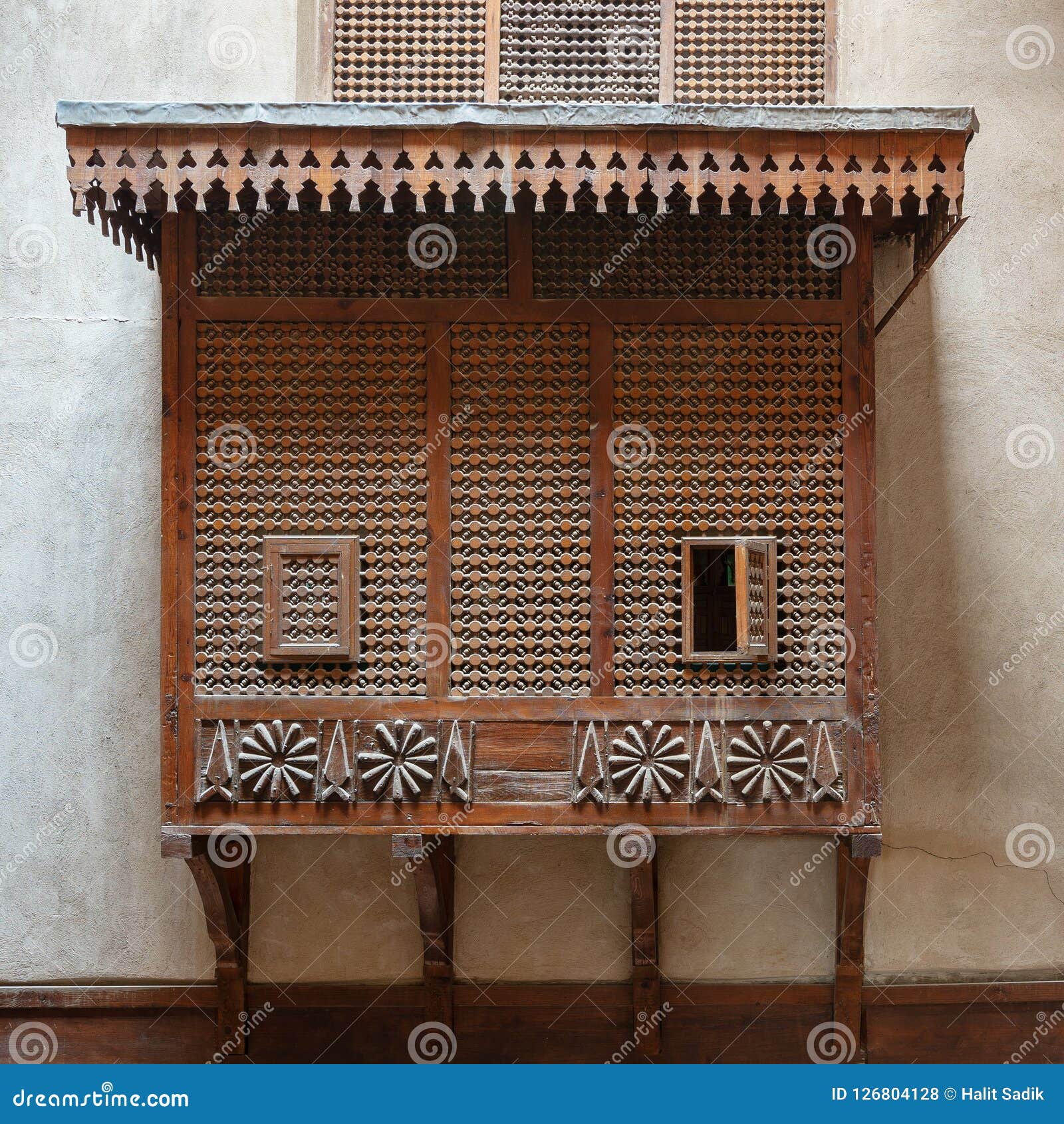 mamluk era style oriel window covered by interleaved wooden grid mashrabiya on stone wall, cairo, egypt