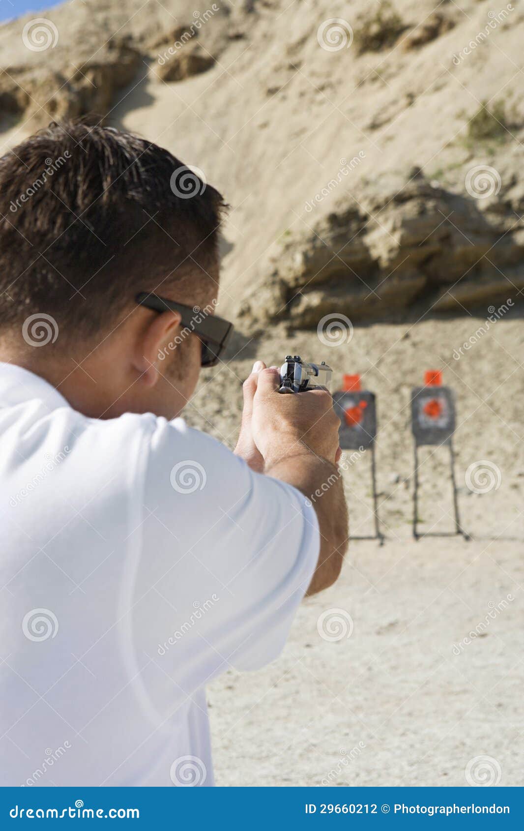 man aiming hand gun at firing range