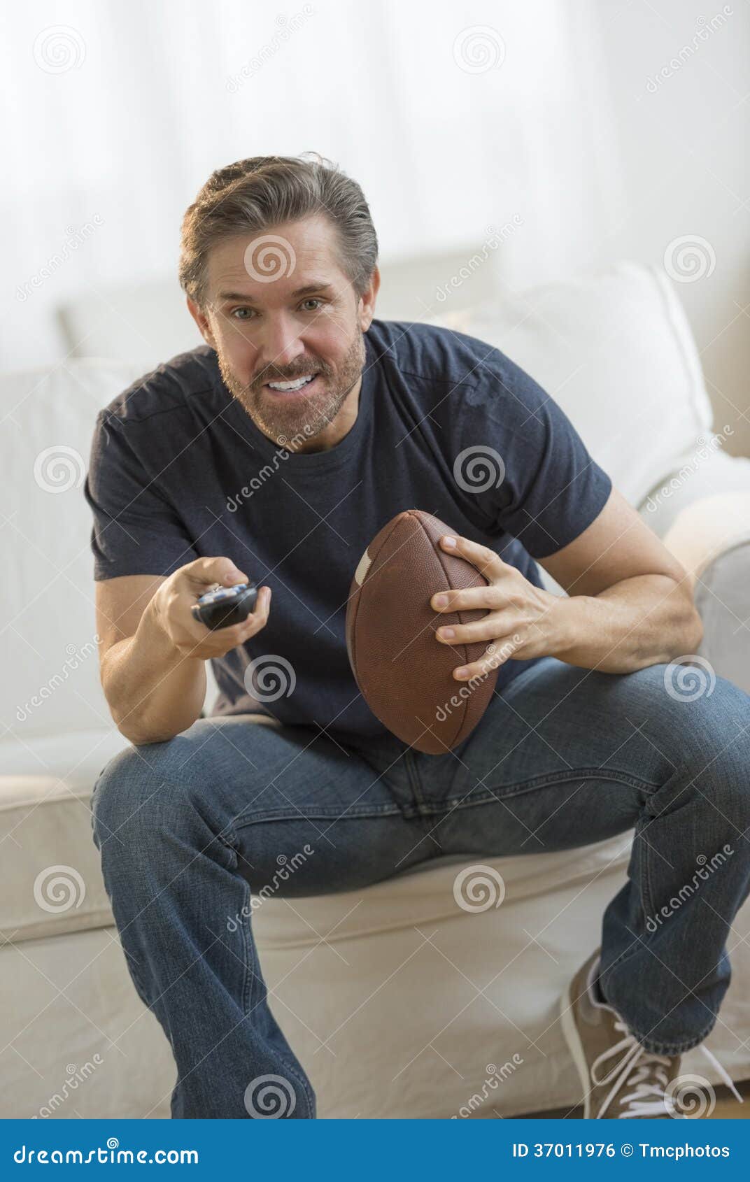 Man with American Football Watching TV Stock Photo