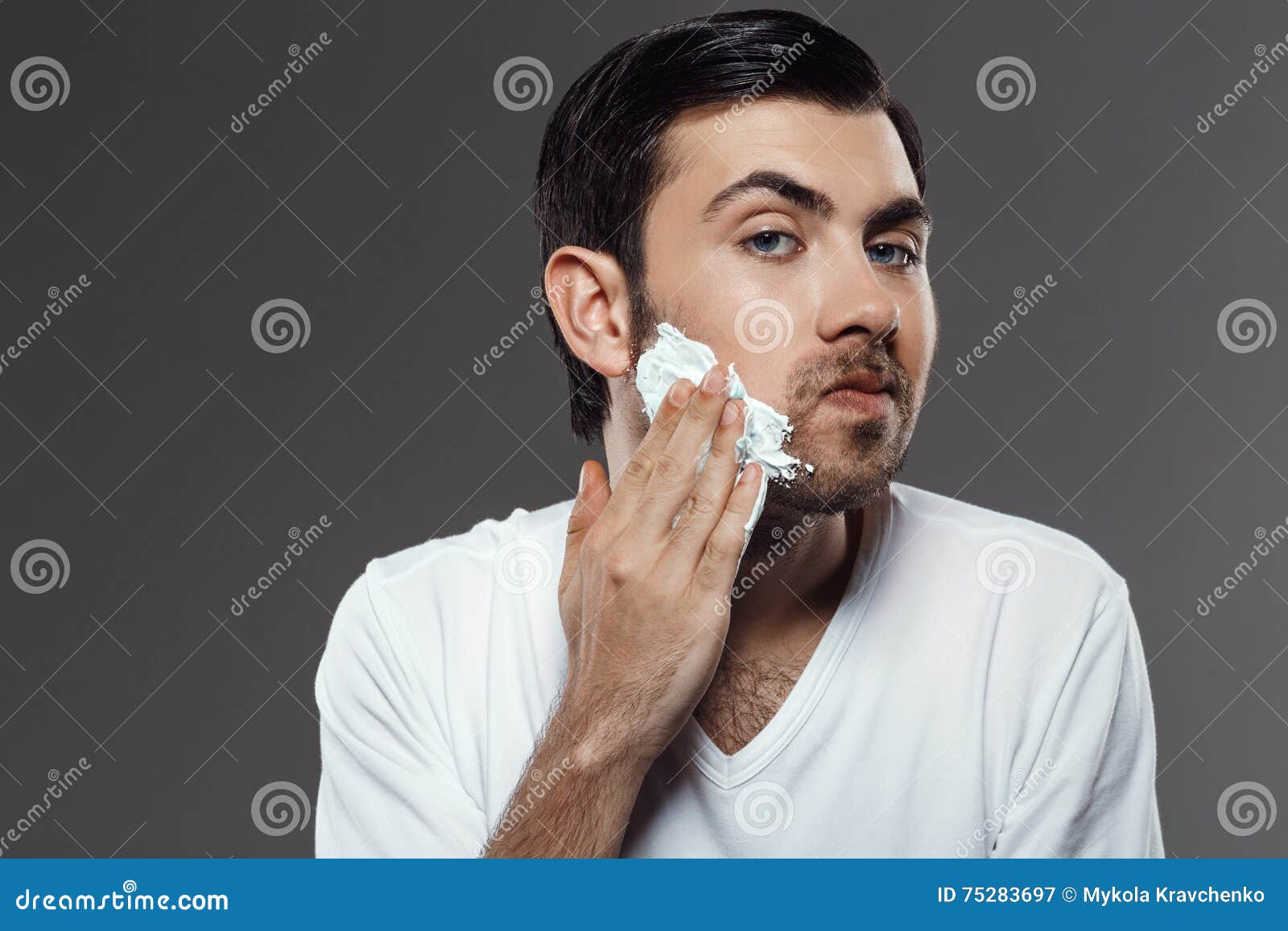 Man Applying Cream For Shave On Face Over Grey Background. Stock Image