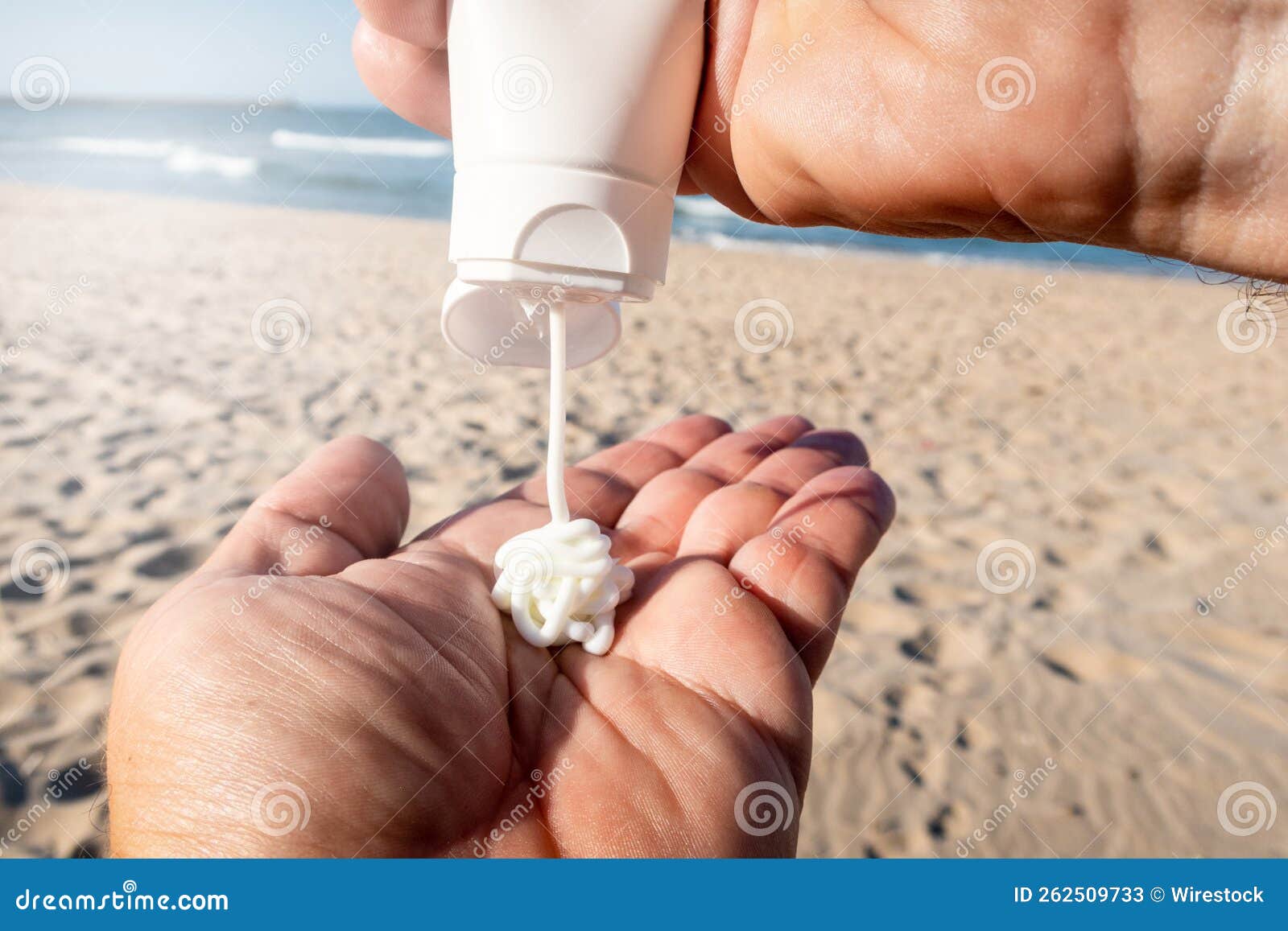 Man Applying Sunscreen Cream To His Hands on the Beach Stock Image