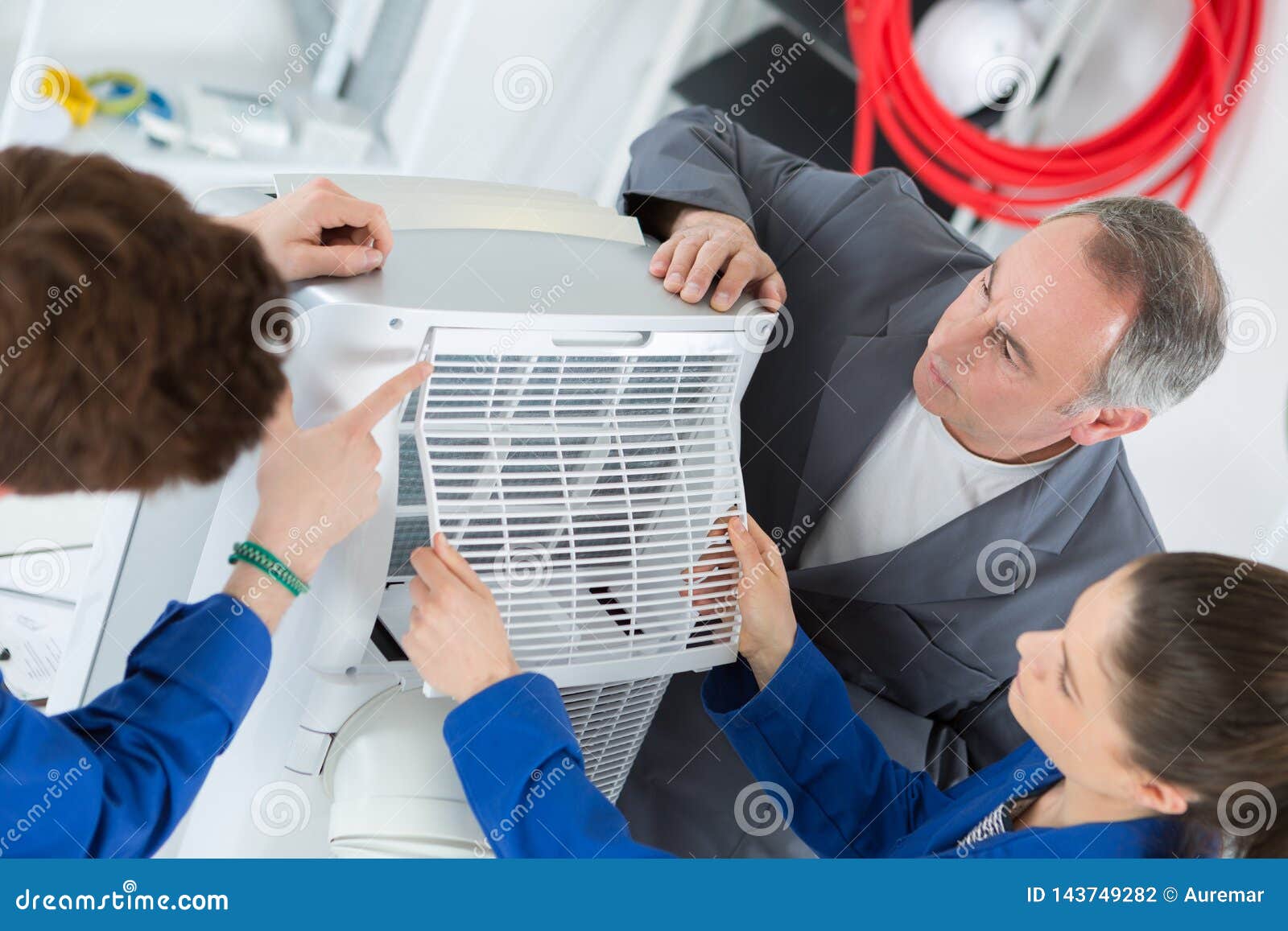 Man and Apprentices Cleaning Air Conditioning System Stock Photo