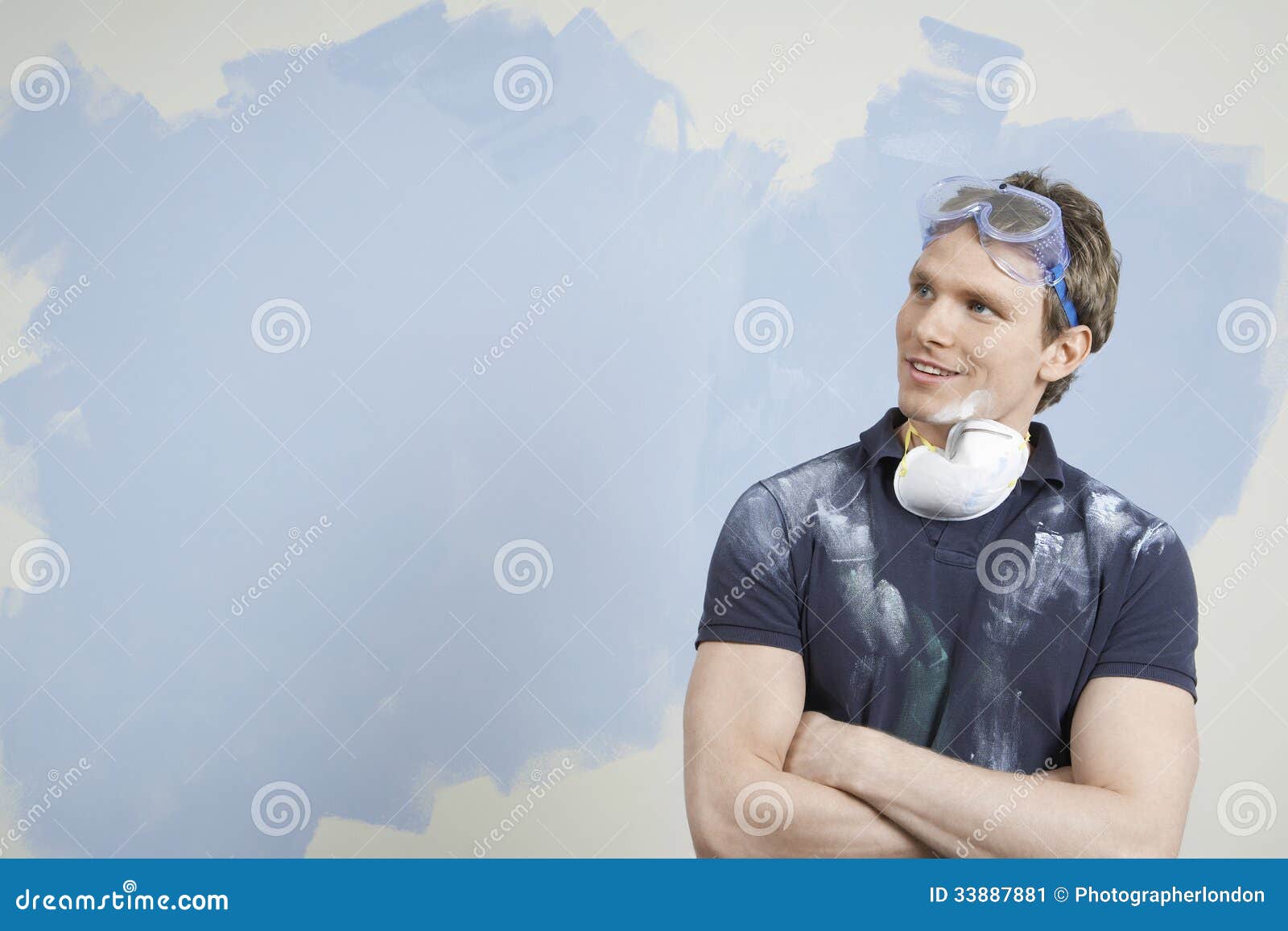 man with arms crossed against incomplete painted wall