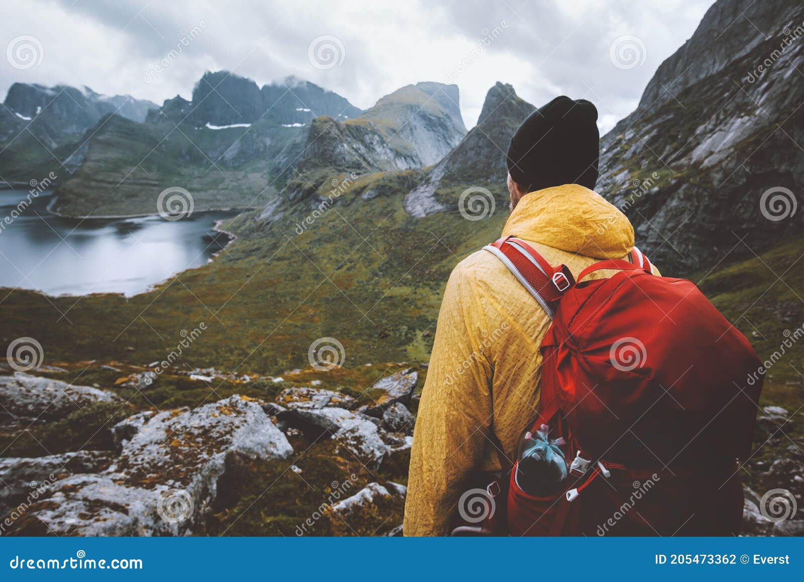 man with backpack hiking in mountains travel survival alone in wilderness of norway