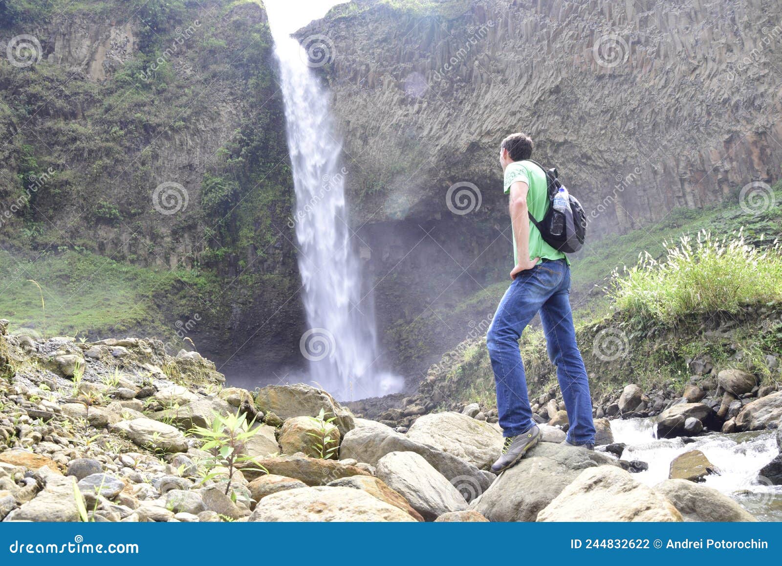 a man with a backpack is standing in front of a waterfall in banos de agua santa, cascada manto de la novia. banos