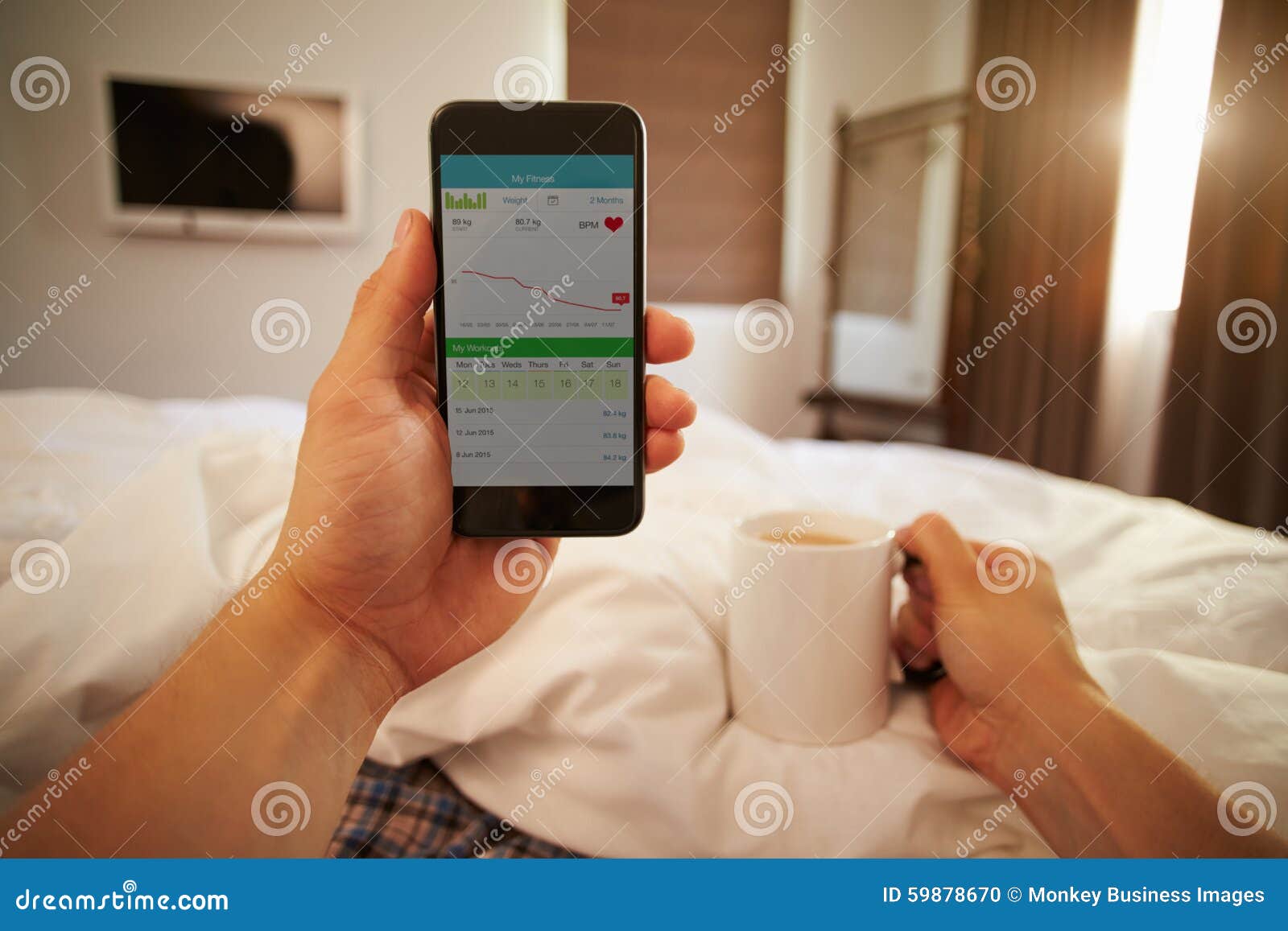 man in bed looking at health monitoring app on mobile phone