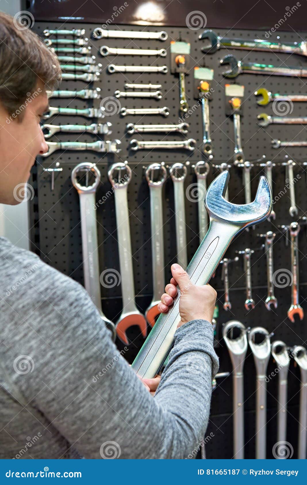 Man with Big Wrench Near Wall with Tools in Store Stock Image Image