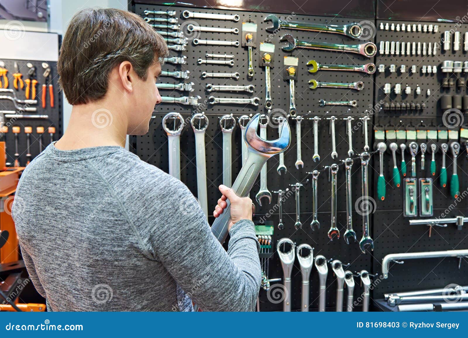 Man with Big Wrench Near Wall with Tools in Store Stock Image Image