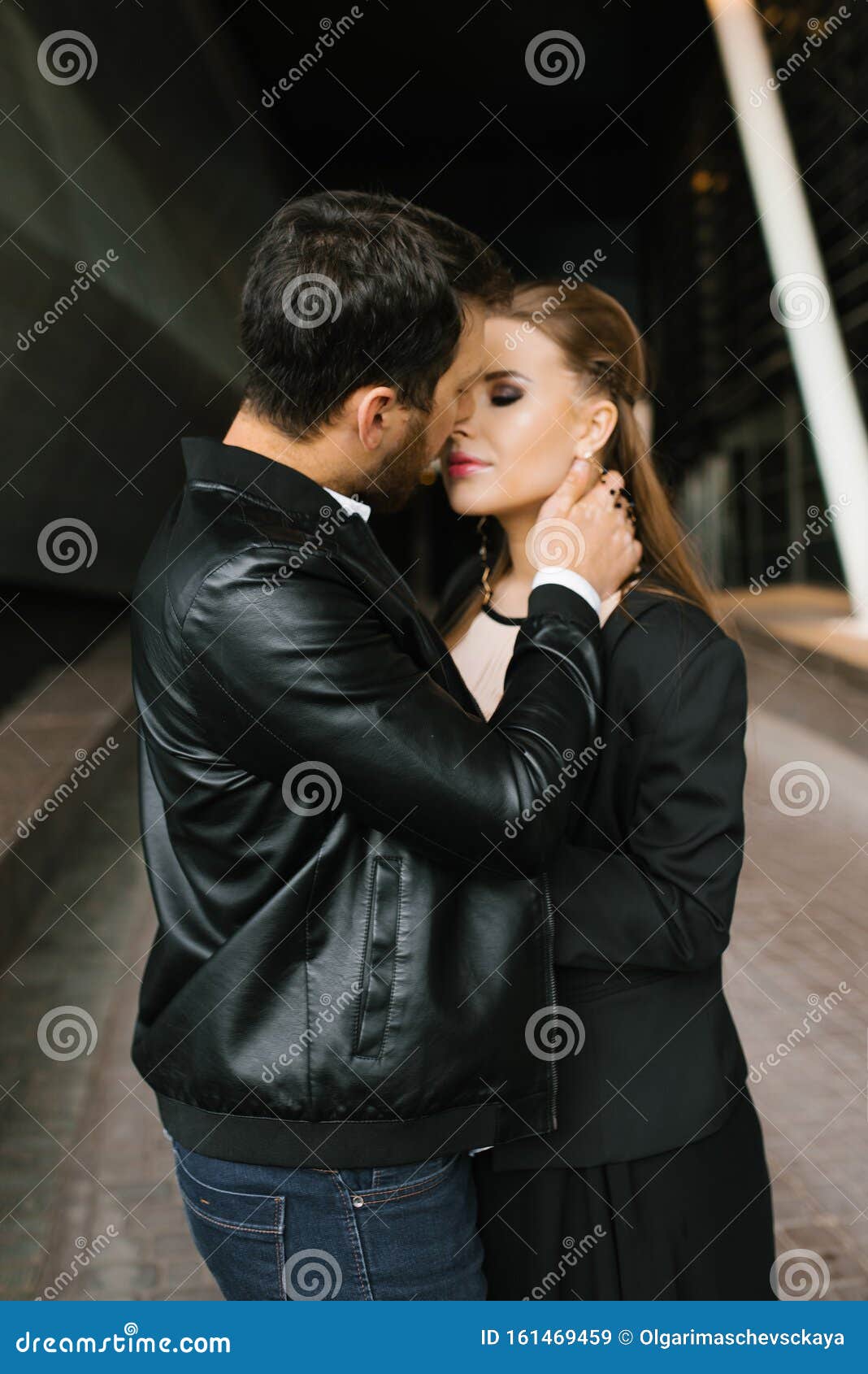 A Man in a Black Jacket and a Woman in a Black Jacket, Hugging Standing ...