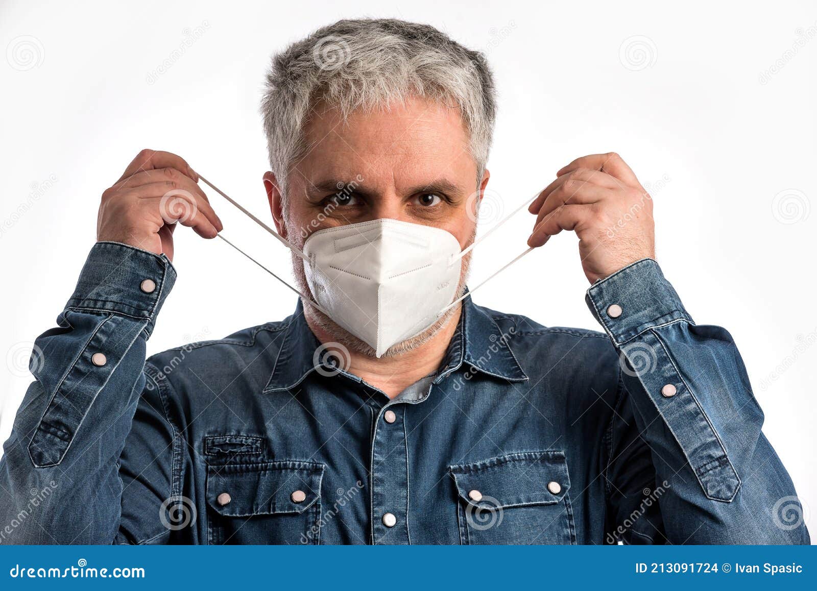 man in blue jeans shirt puts on a face mask