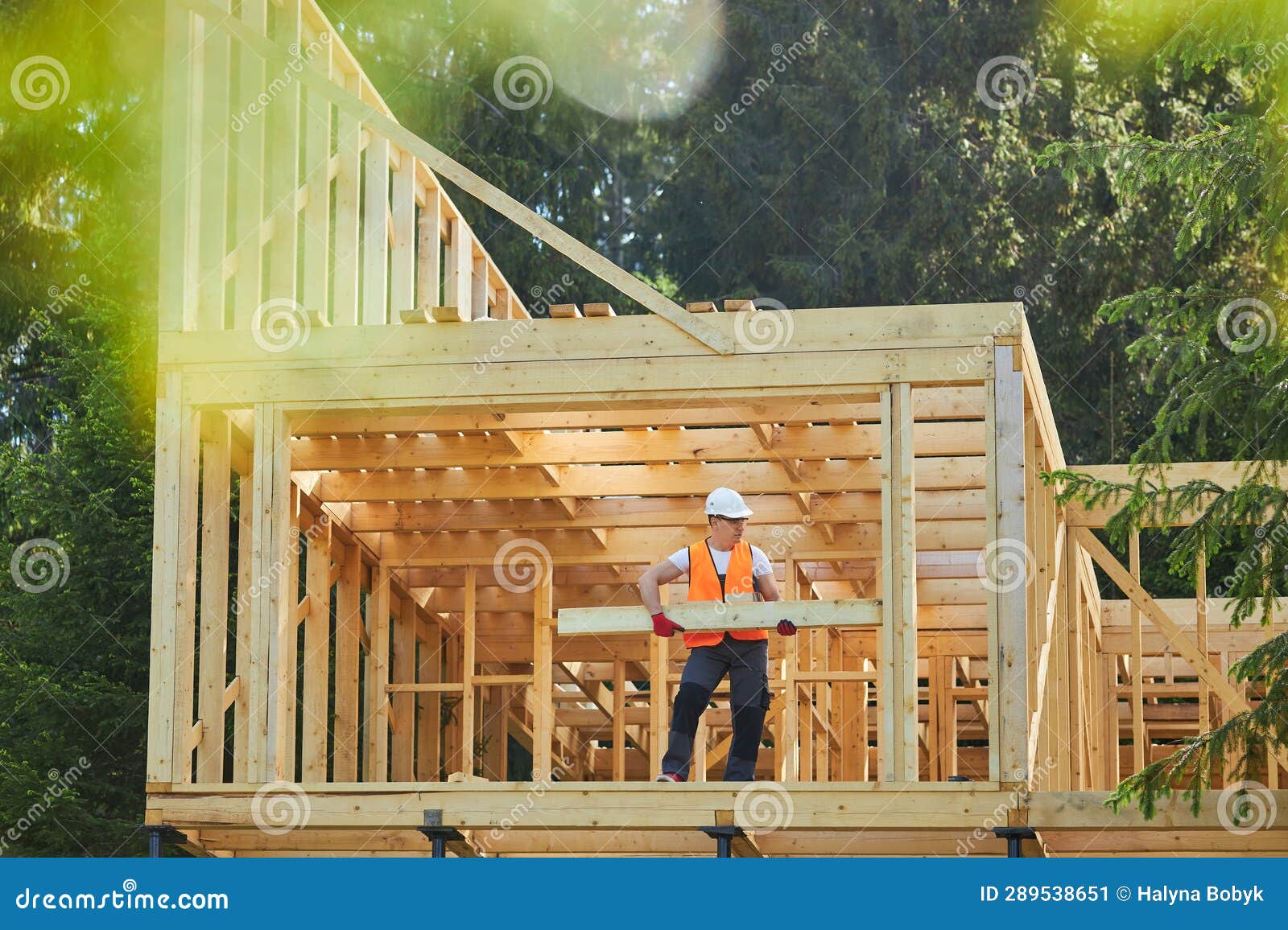 man, builder, worker building wooden house in forest, in sunny weather, in summer.