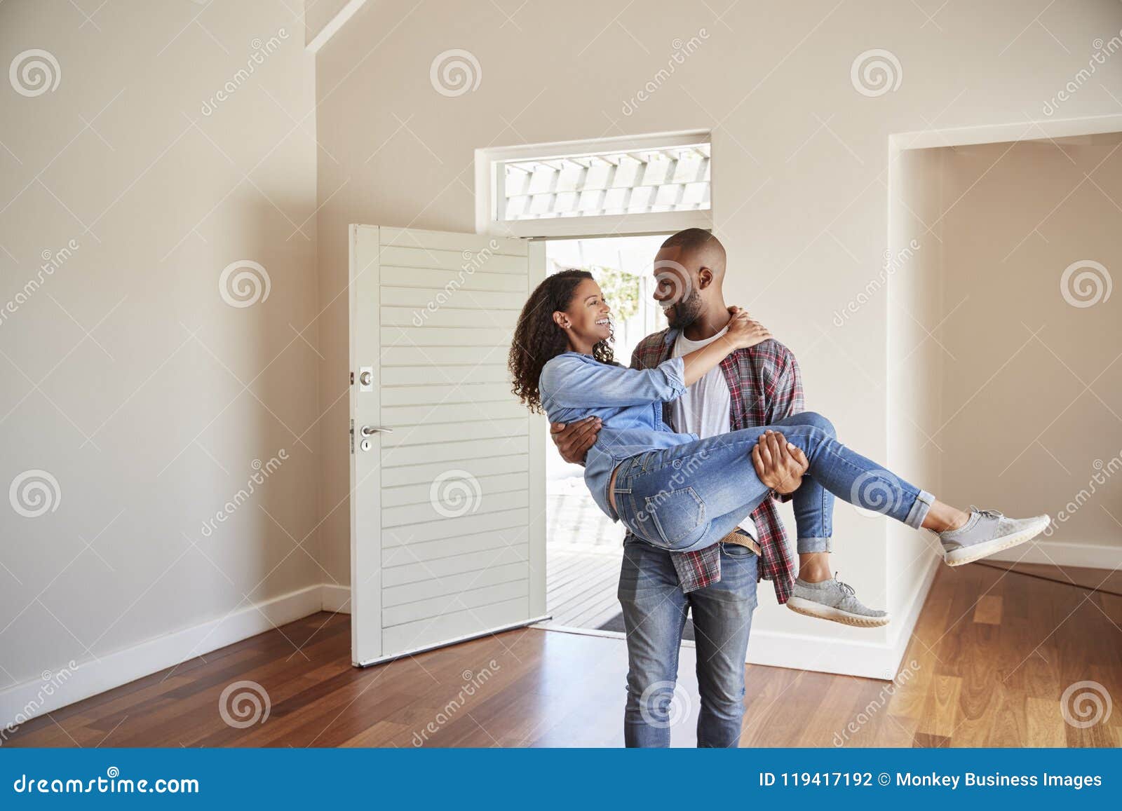 Man Carrying Woman Over Threshold Of Doorway In New Home Stock