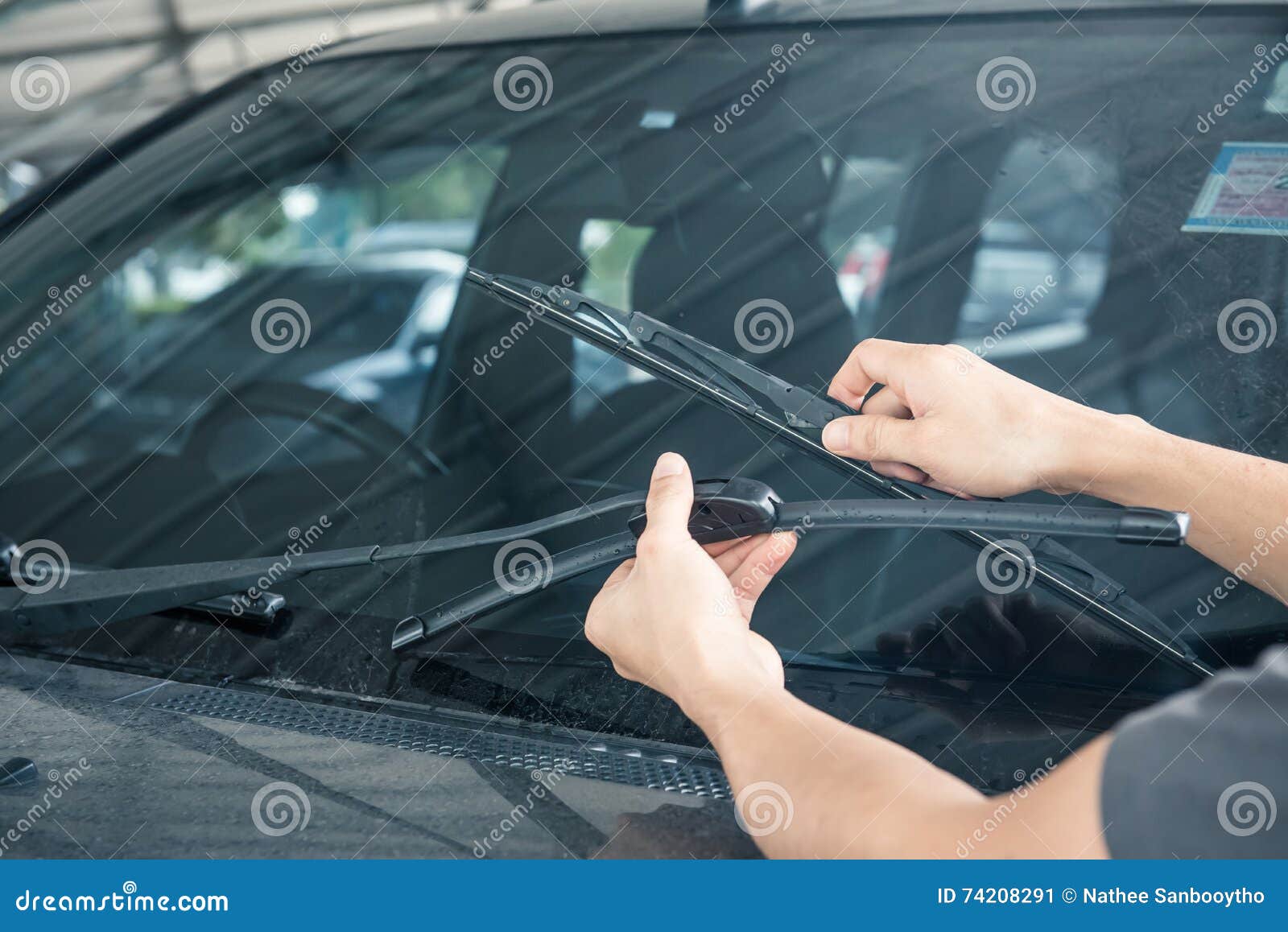 man is changing windscreen wipers on a car