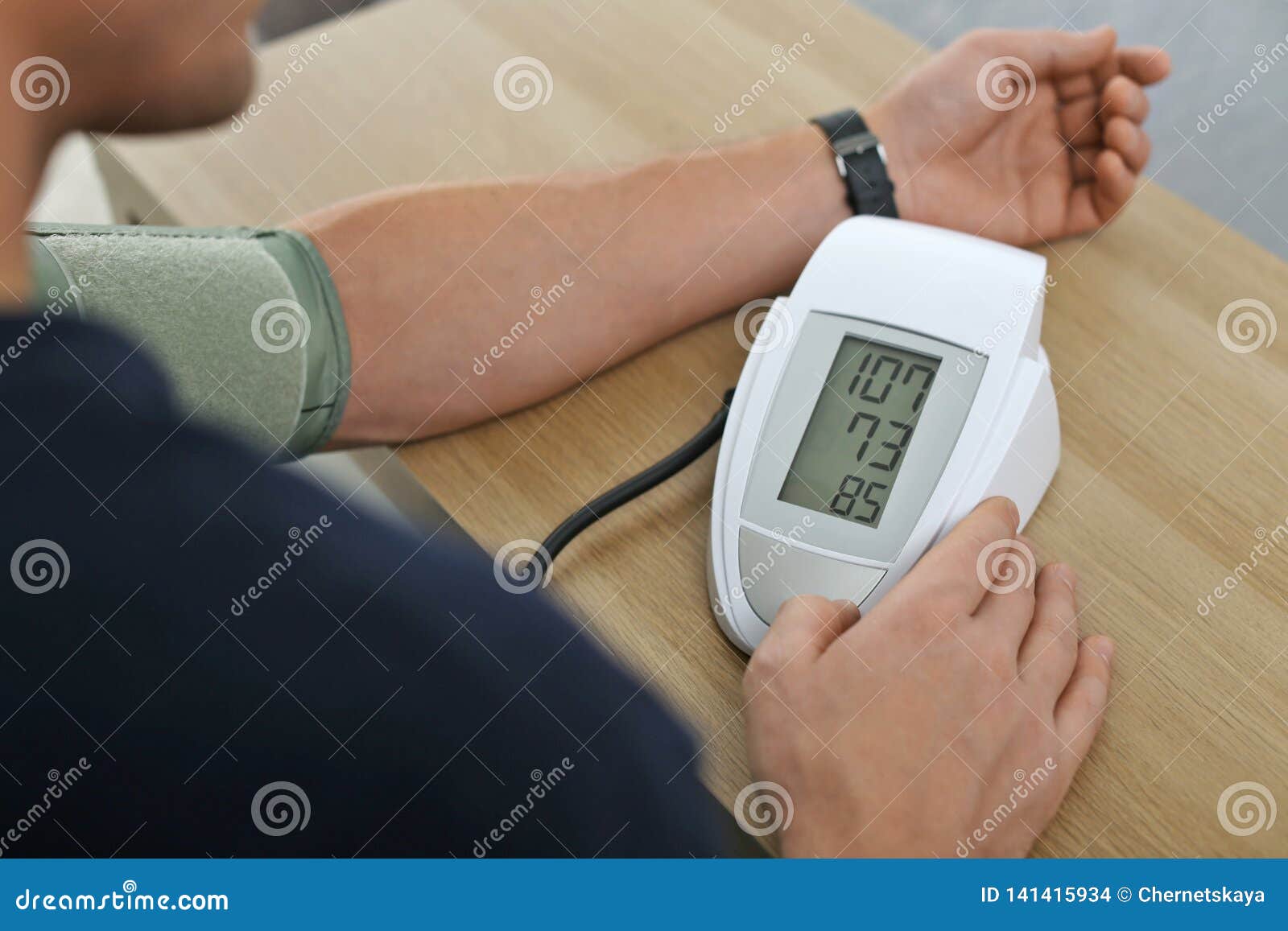 Man Checking Blood Pressure With Sphygmomanometer At Table Indoors