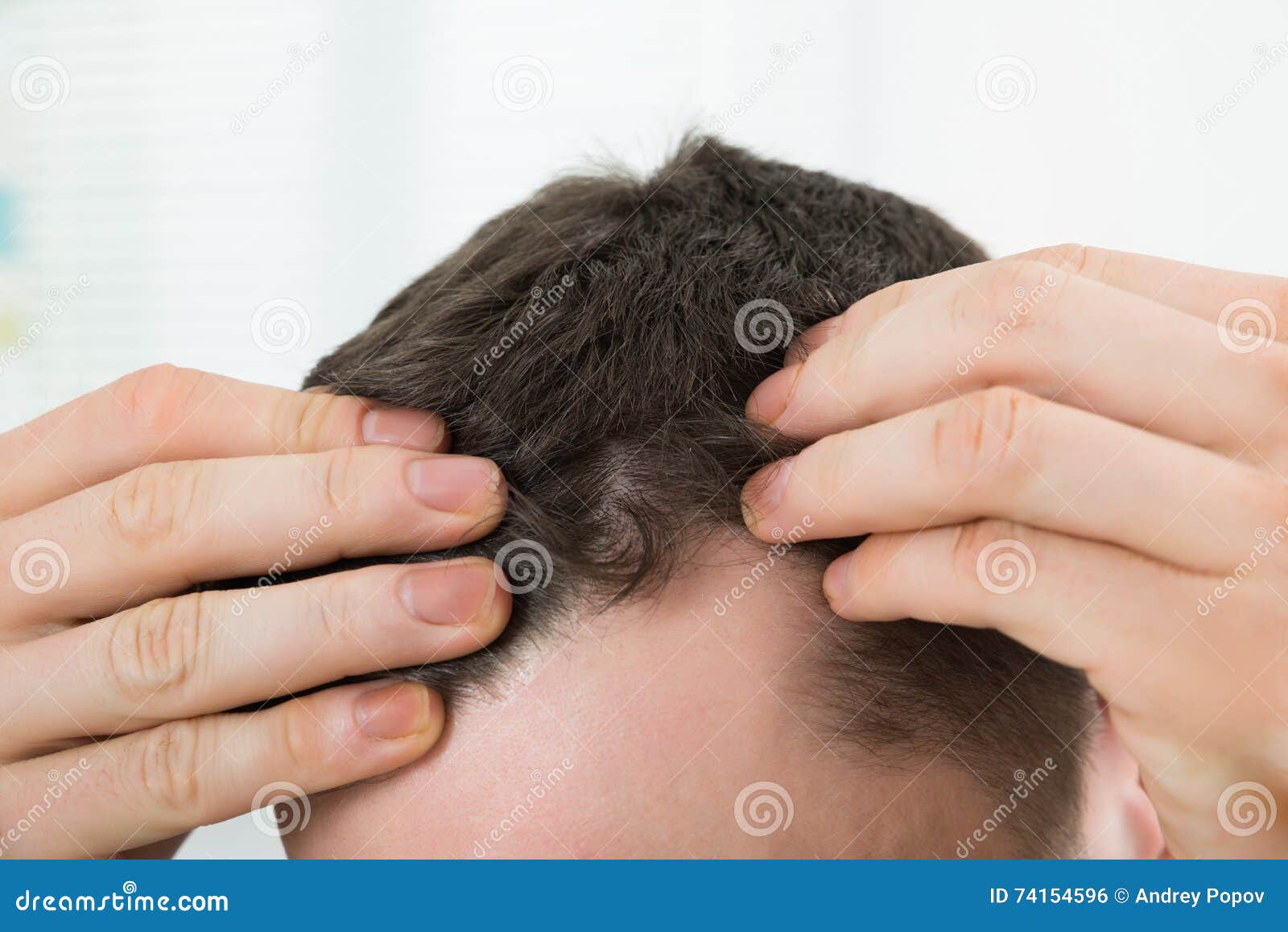 man checking hairline at home
